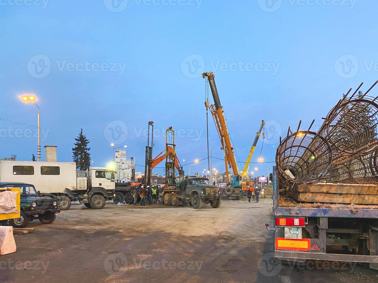 construction of a broken bridge on a busy road. construction machinery on the site erects concrete blocks. truck carries a metal frame photo