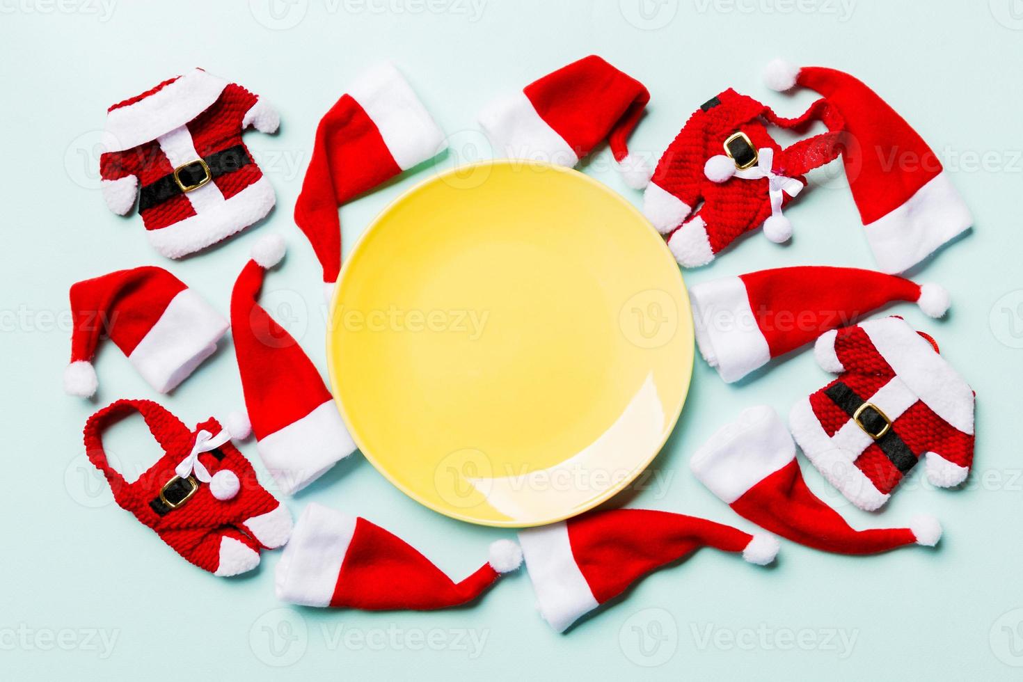 Festive set of plate decorated with Santa Claus hat on colorful background. Top view christmas dinner concept photo