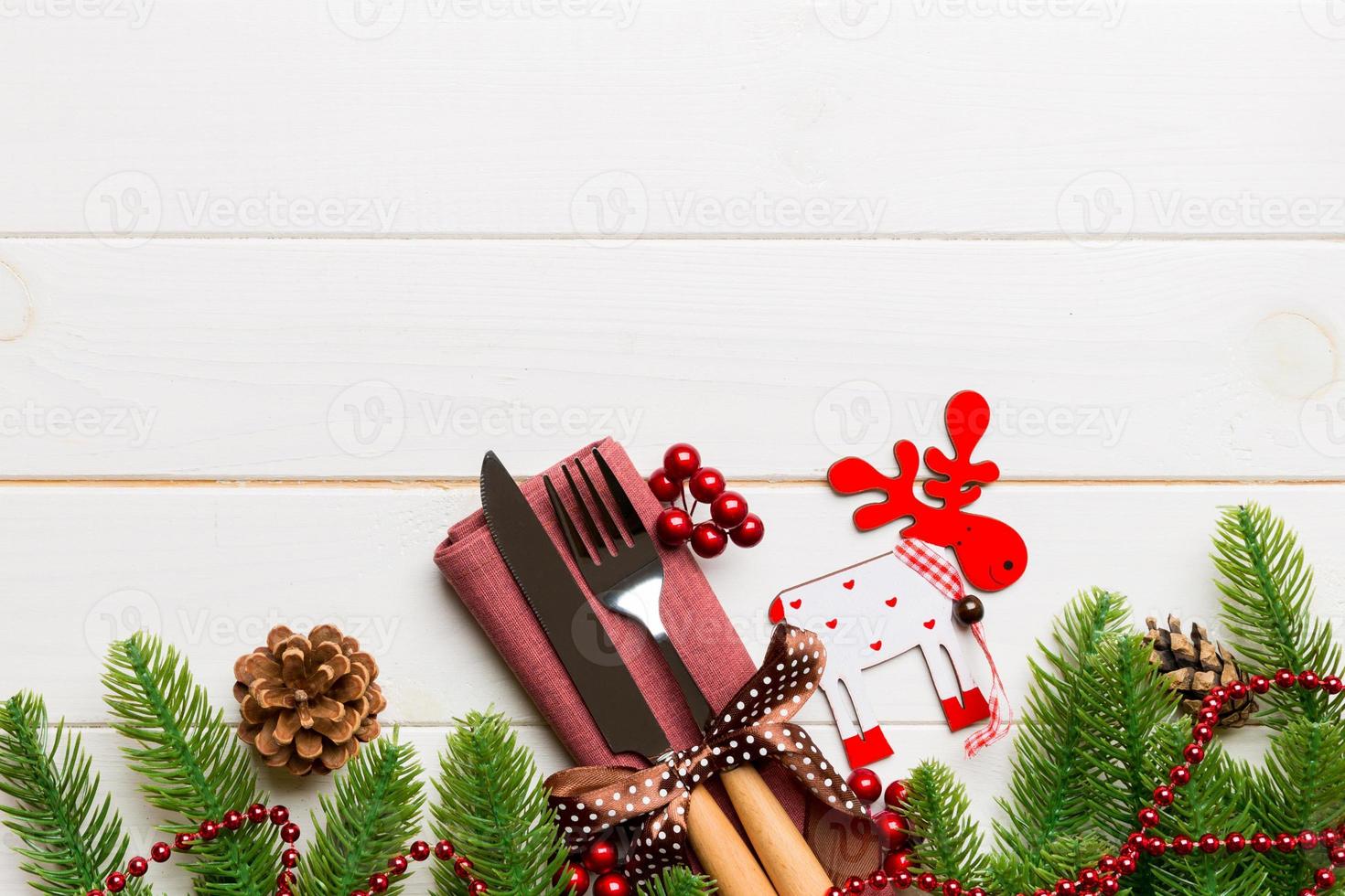 Top view of flatware tied up with ribbon on napkin on wooden background. Christmas decorations and reindeer with empty space for your design. New Year holiday concept photo
