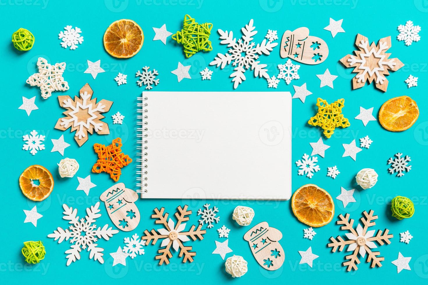 Top view of notebook on blue background with New Year toys and decorations. Christmas time concept photo