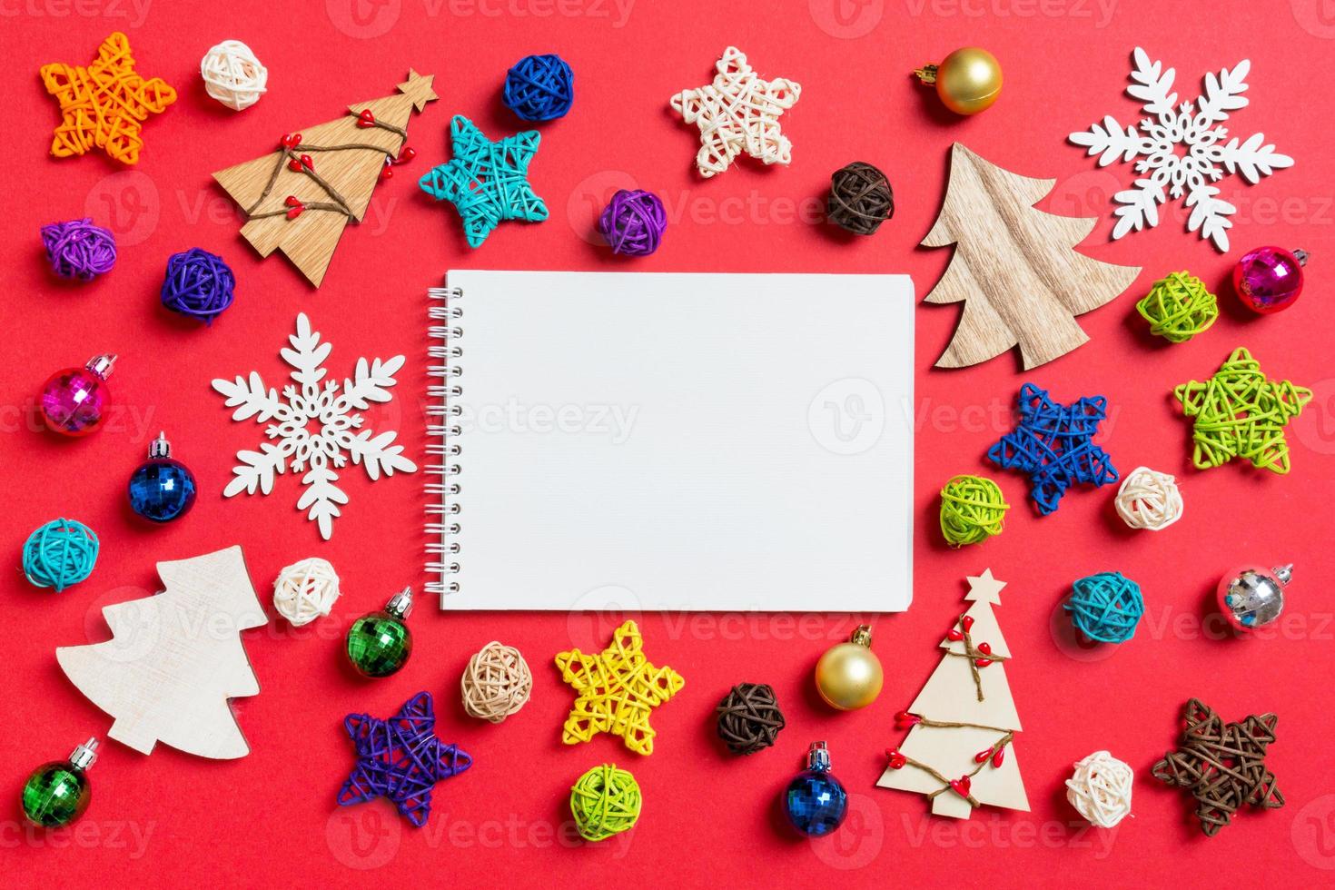 Top view of notebook on red background made of holiday decorations and toys. Christmas ornament concept photo