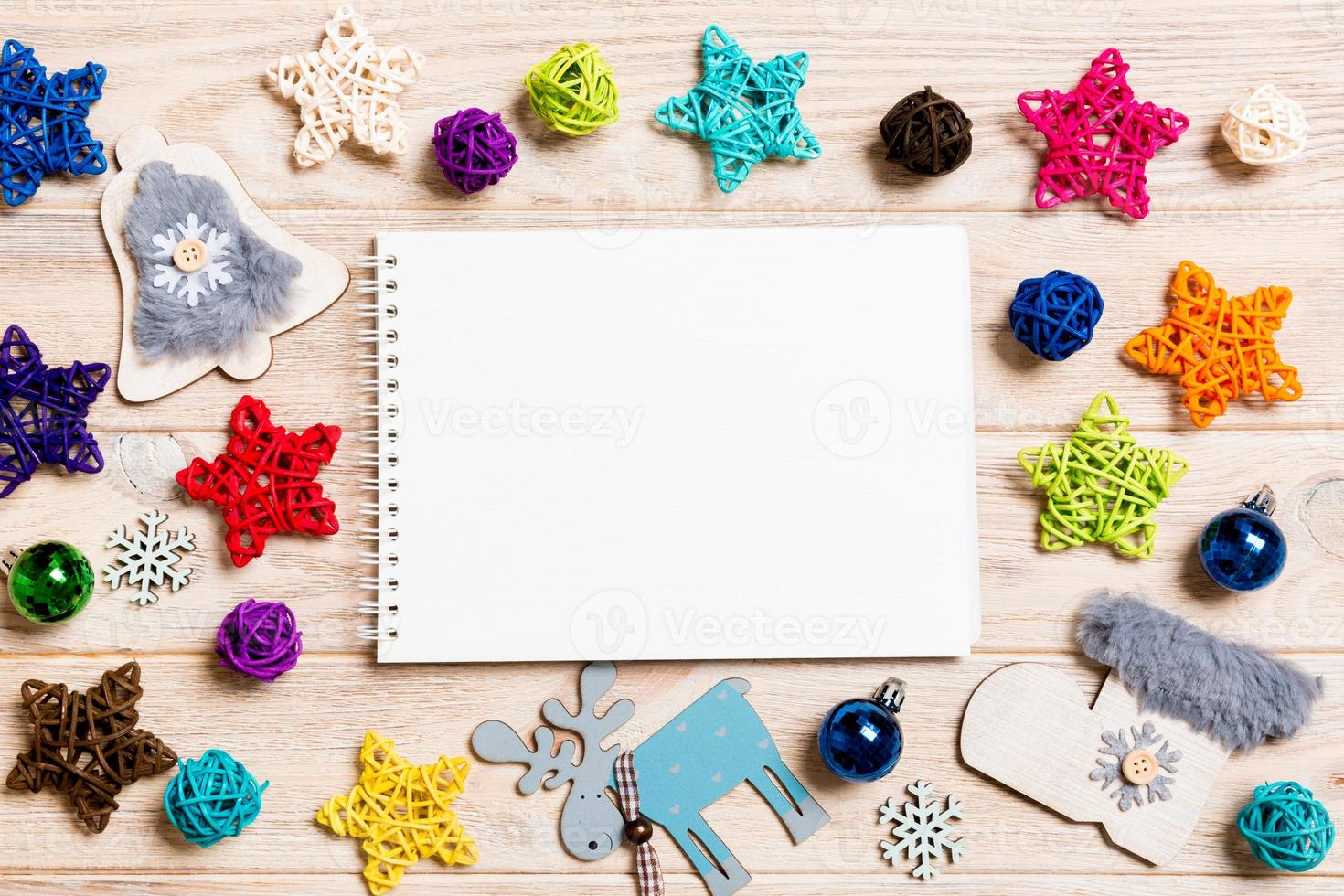 Top view of notebook on wooden background made of Christmas decorations. New Year concept photo