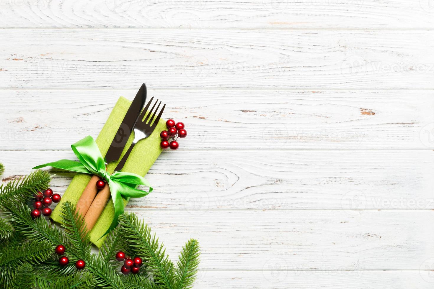 Top view of christmas decorations on wooden background. Fork and knife on napkin tied up with ribbon and empty space for your design. New year pattern concept photo