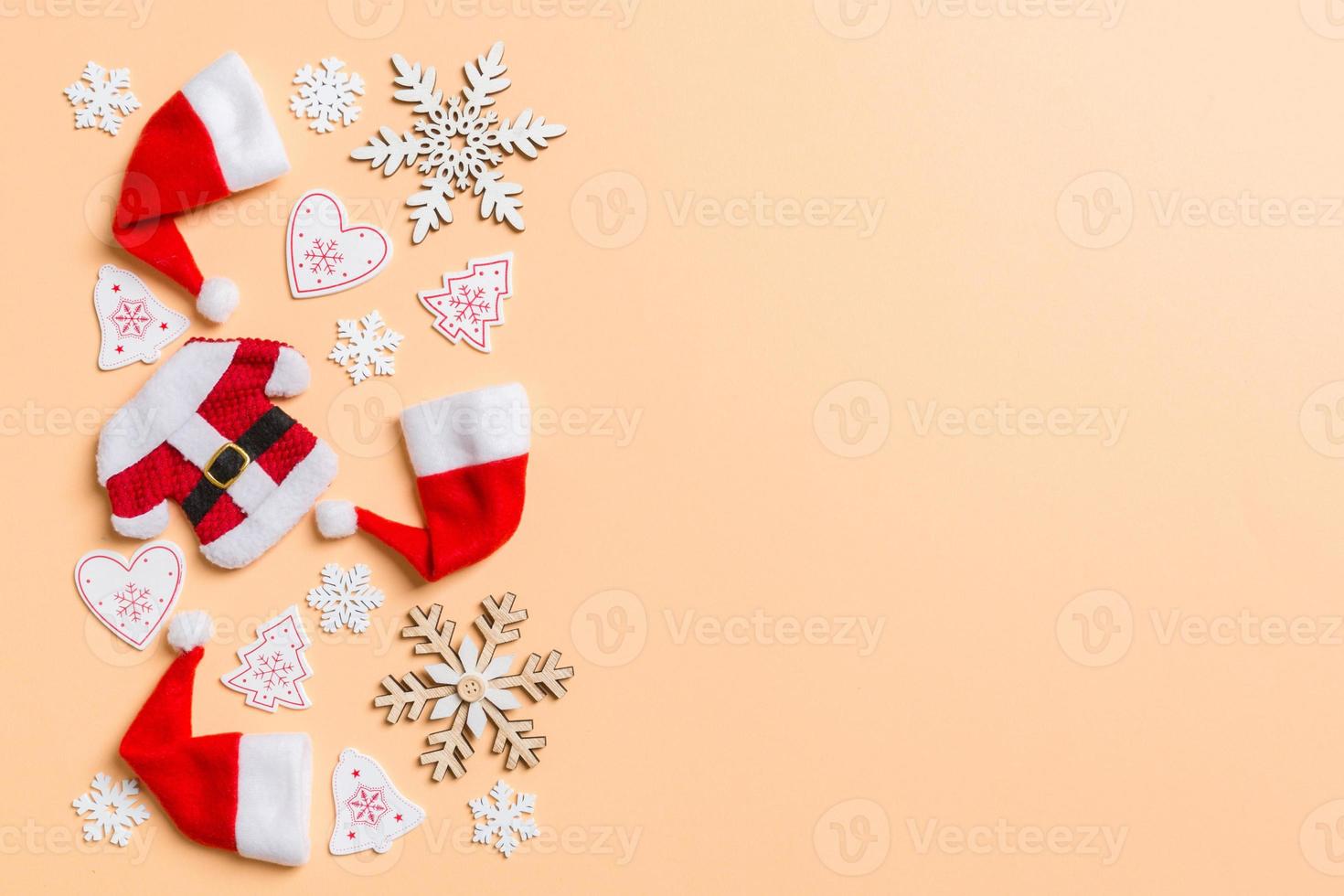 Top view of Christmas decorations and Santa hats on orange background. Happy holiday concept with copy space photo