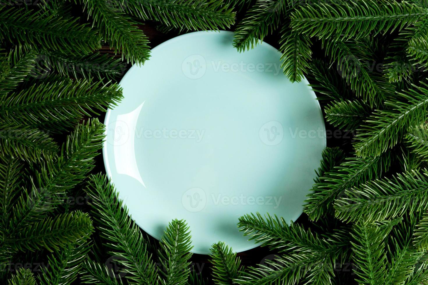 Top view holiday plate among green fir tree branches. Christmas dinner with copy space photo