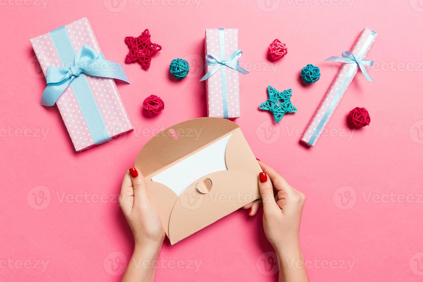 Top view of woman holding an envelope on pink background made of holiday decorations. Christmas time concept photo