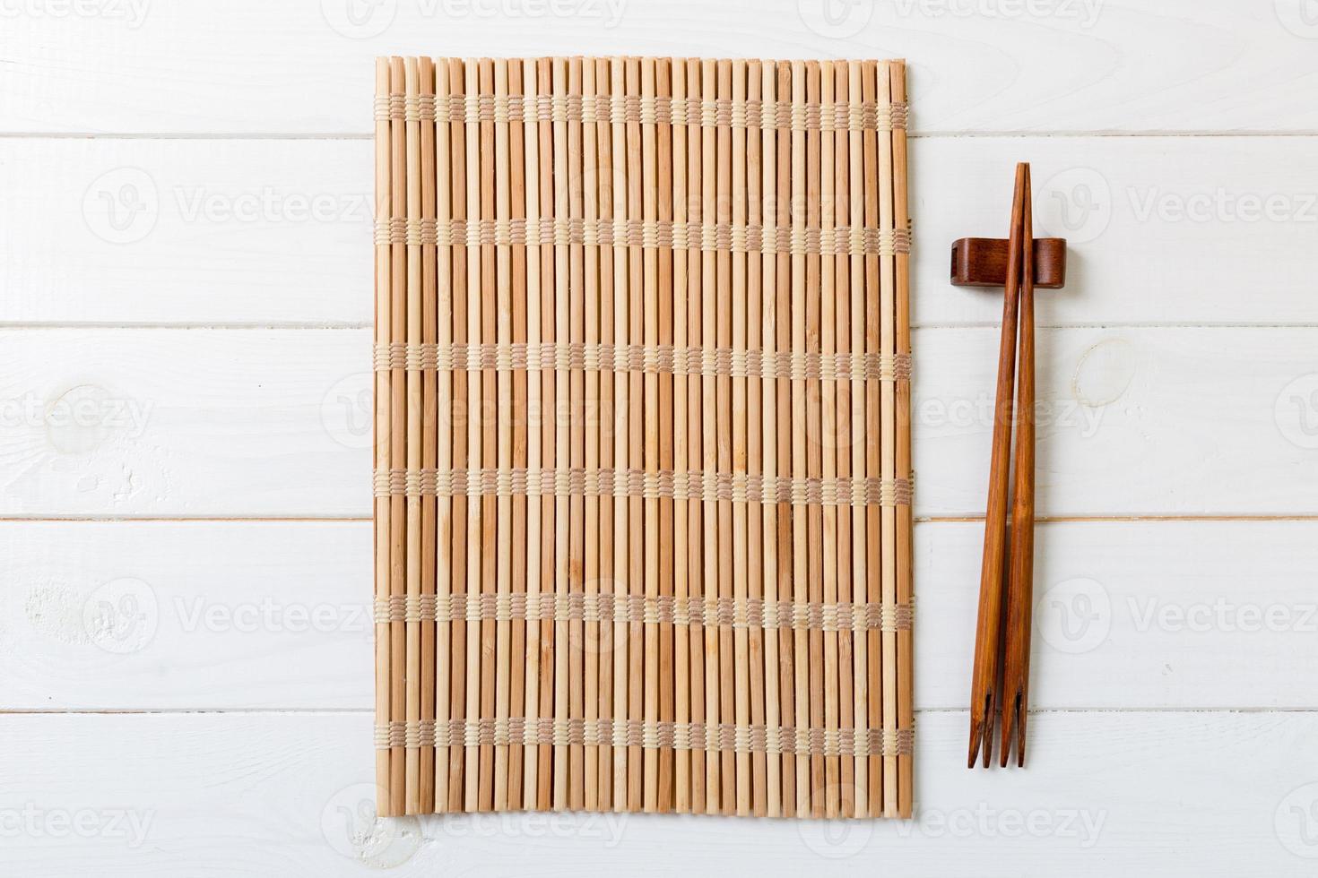 two sushi chopsticks with empty bamboo mat or wood plate on wooden Background Top view with copy stace photo