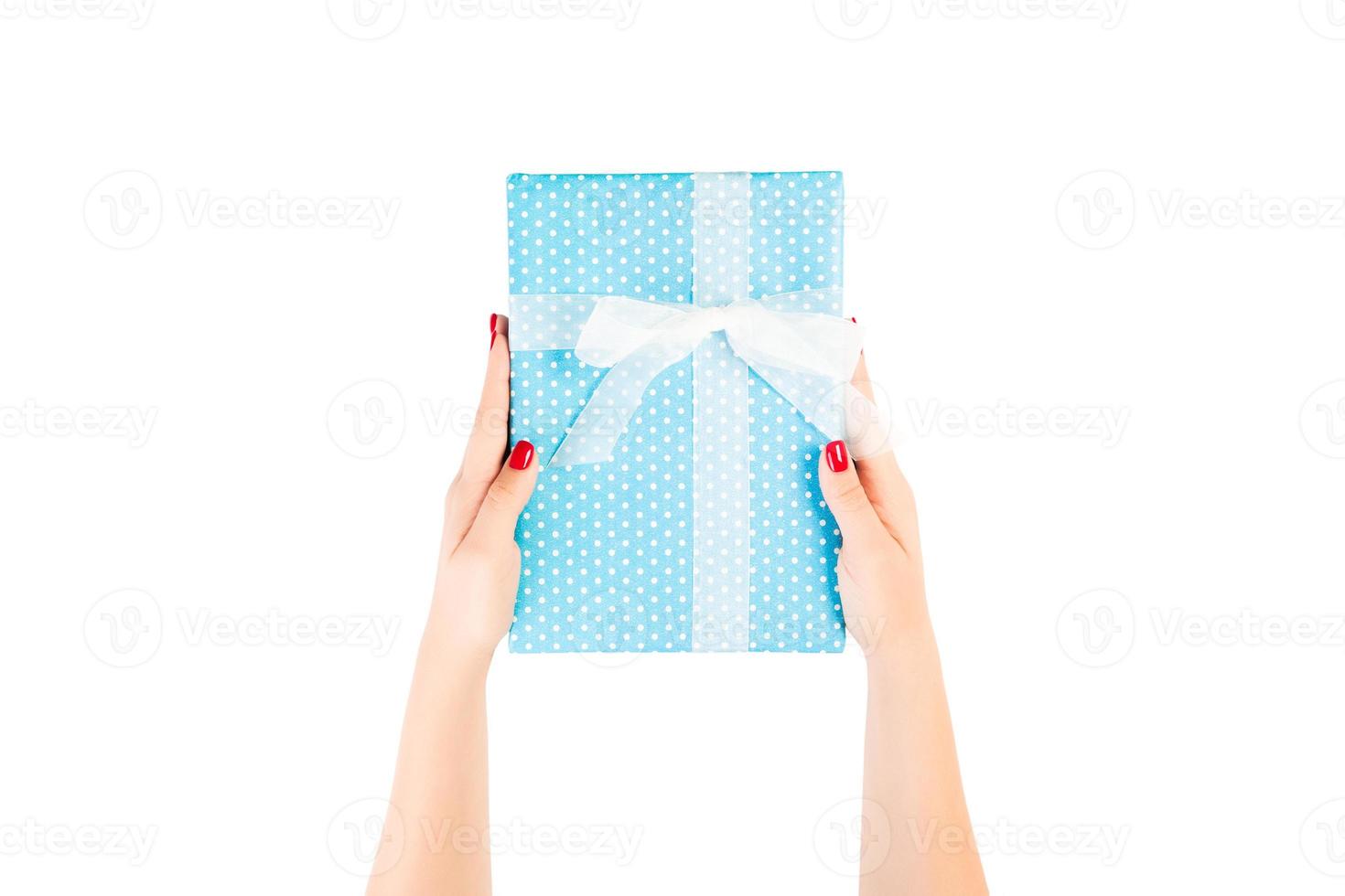 Woman hands give wrapped Christmas or other holiday handmade present in blue paper with white ribbon. Isolated on white background, top view. thanksgiving Gift box concept photo
