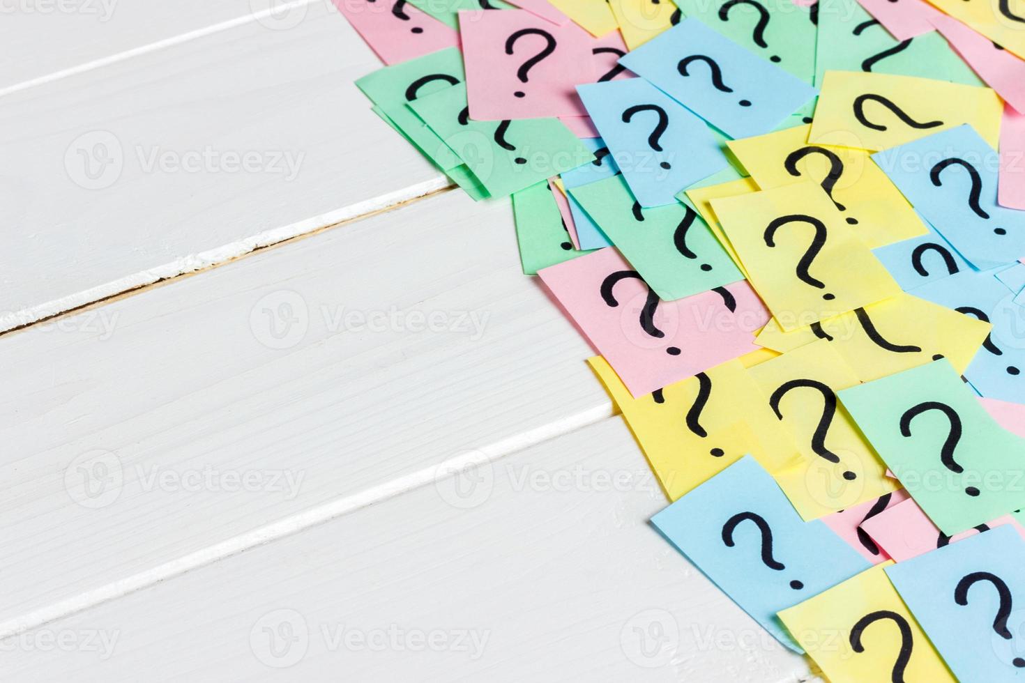 Just a lot of question marks on colored papers on wood background photo
