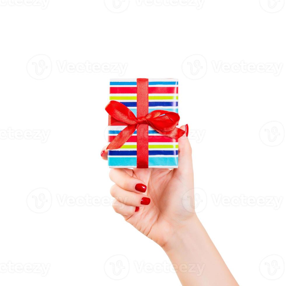 las manos de las mujeres dan Navidad envuelta u otro regalo hecho a mano en papel de colores con cinta roja. aislado sobre fondo blanco, vista superior. concepto de caja de regalo de acción de gracias foto