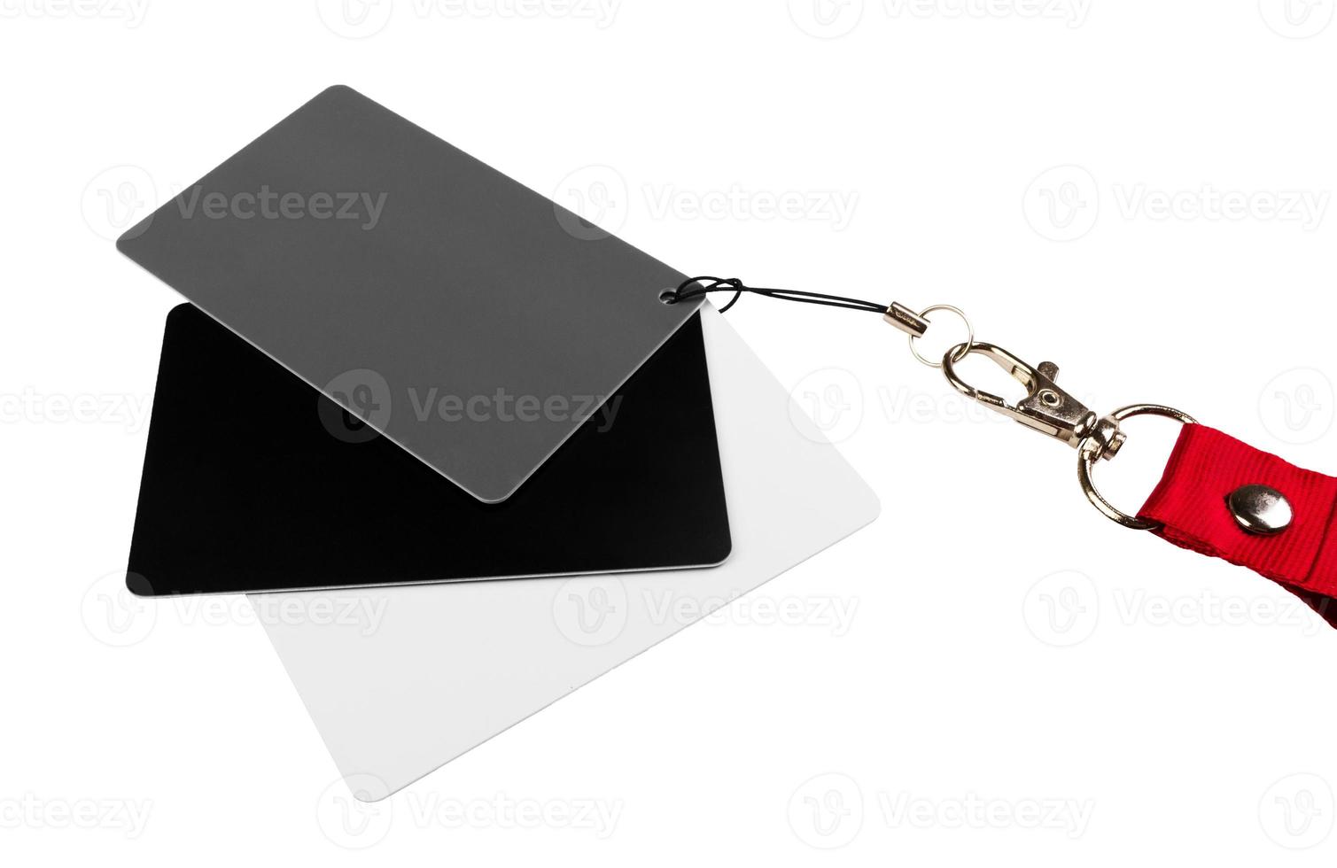 Three cards, one white, one grey and one black, attached together, and on a red strap, on a white surface. isolated on white background photo