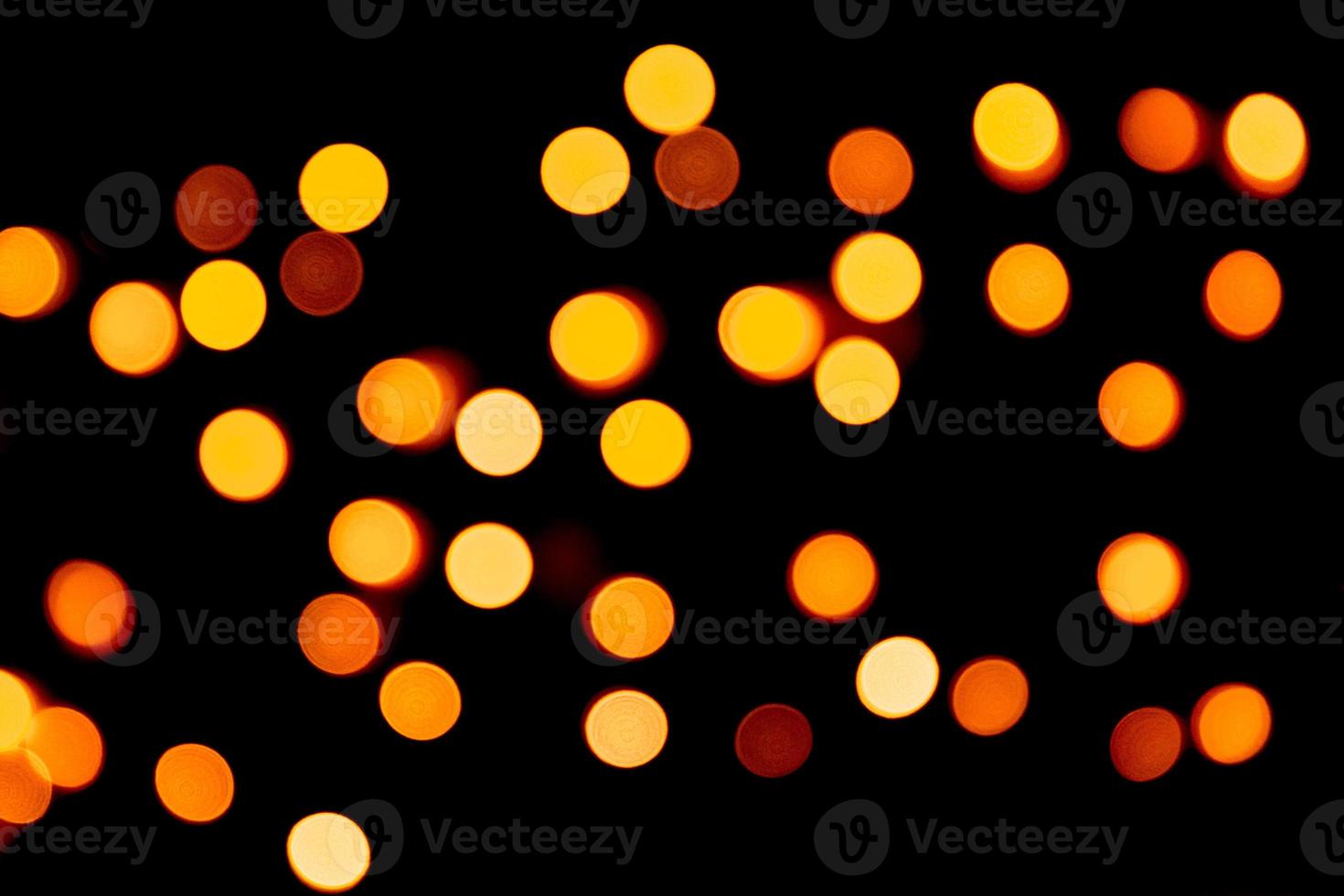 Holiday glowing gold backdrop. defocused and blurred many round yellow light on Christmas black background photo