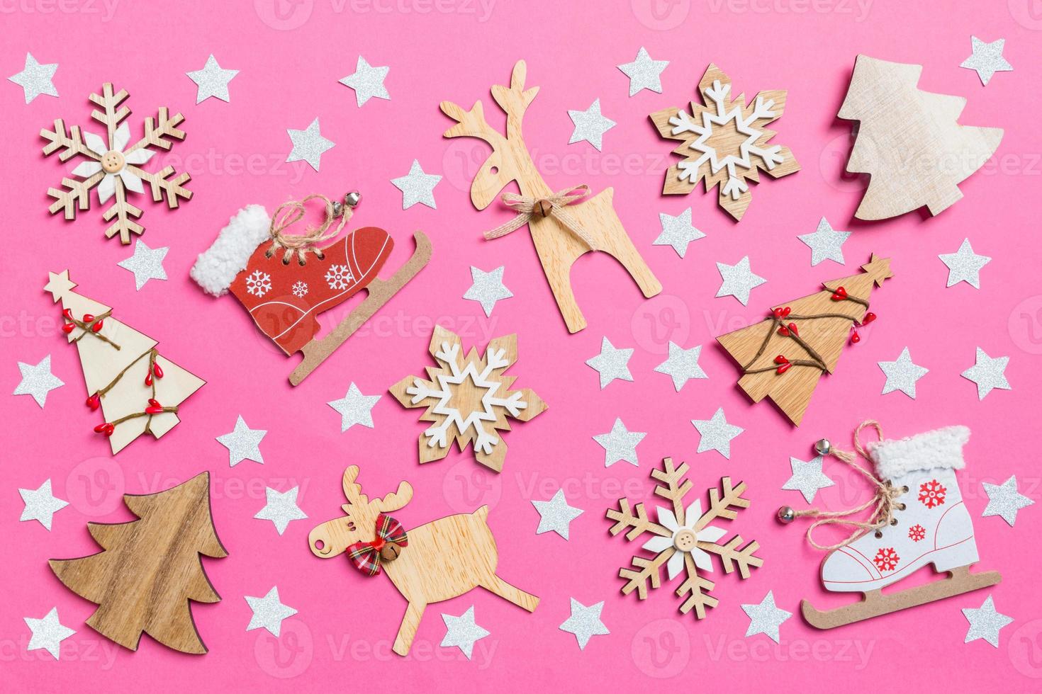 Top view of pink background decorated with festive toys and Christmas symbols reindeers and New Year trees. Holiday concept photo