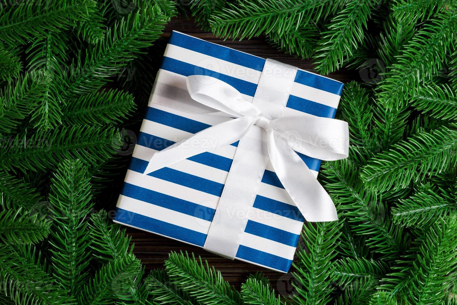 Top view of festive gift box decorated with green fir tree branches. Christmas time with copy space photo