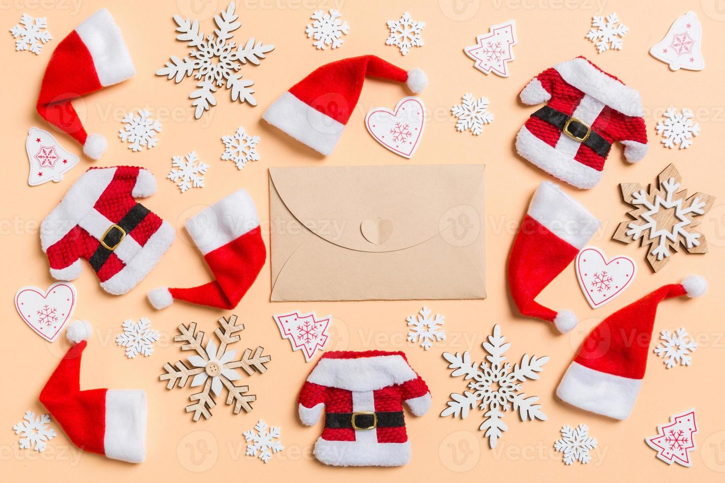 Top view of craft envelope with Christmas decorations and Santa hats on orange background. Happy holiday concept photo