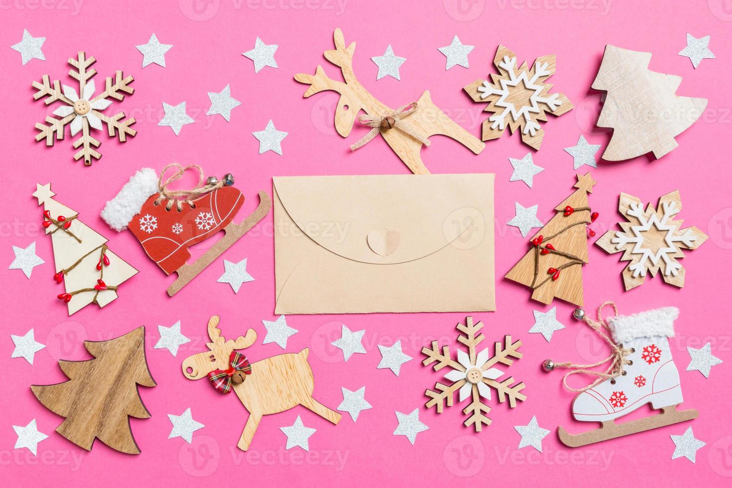 Top view of craft envelope, pink background decorated with festive toys and Christmas symbols reindeers and New Year trees. Holiday concept photo