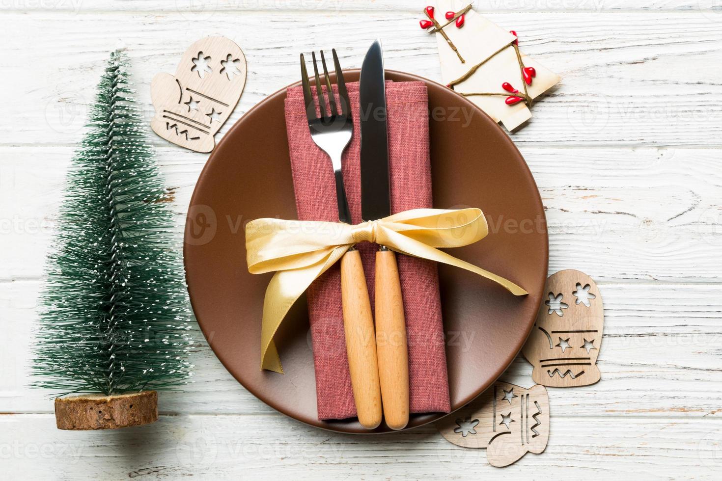 Top view of plate, fork and knife served on Christmas decorated wooden background. New Year Eve concept with copy space photo