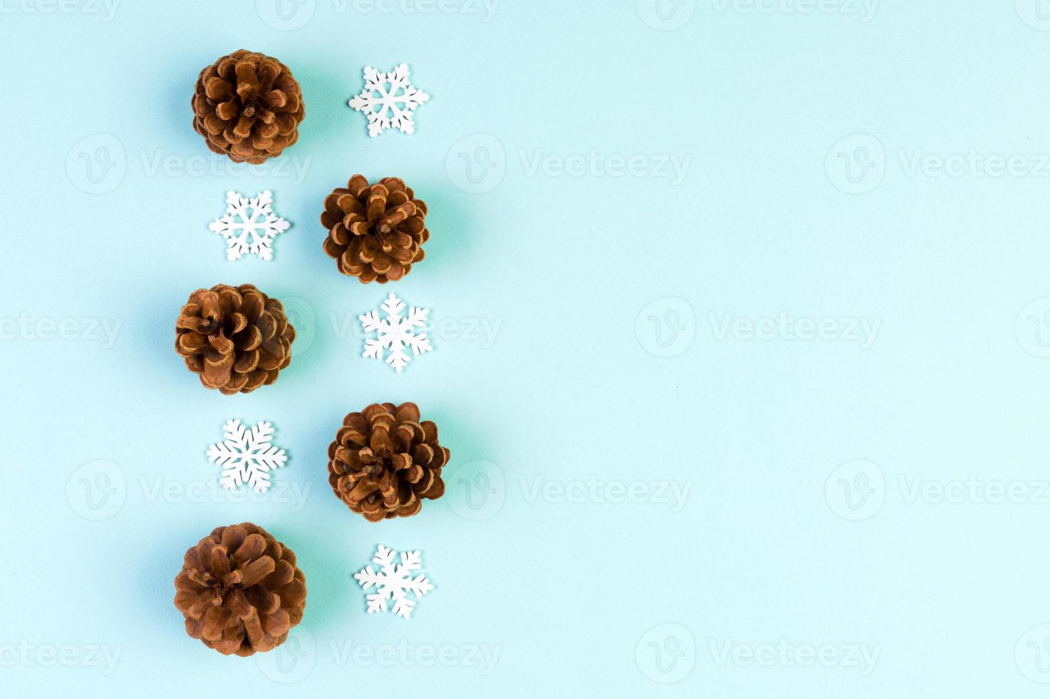 Top view of holiday composition made of pine cones and white snowflakes on colorful background. Winter time and Christmas concept with copy space photo