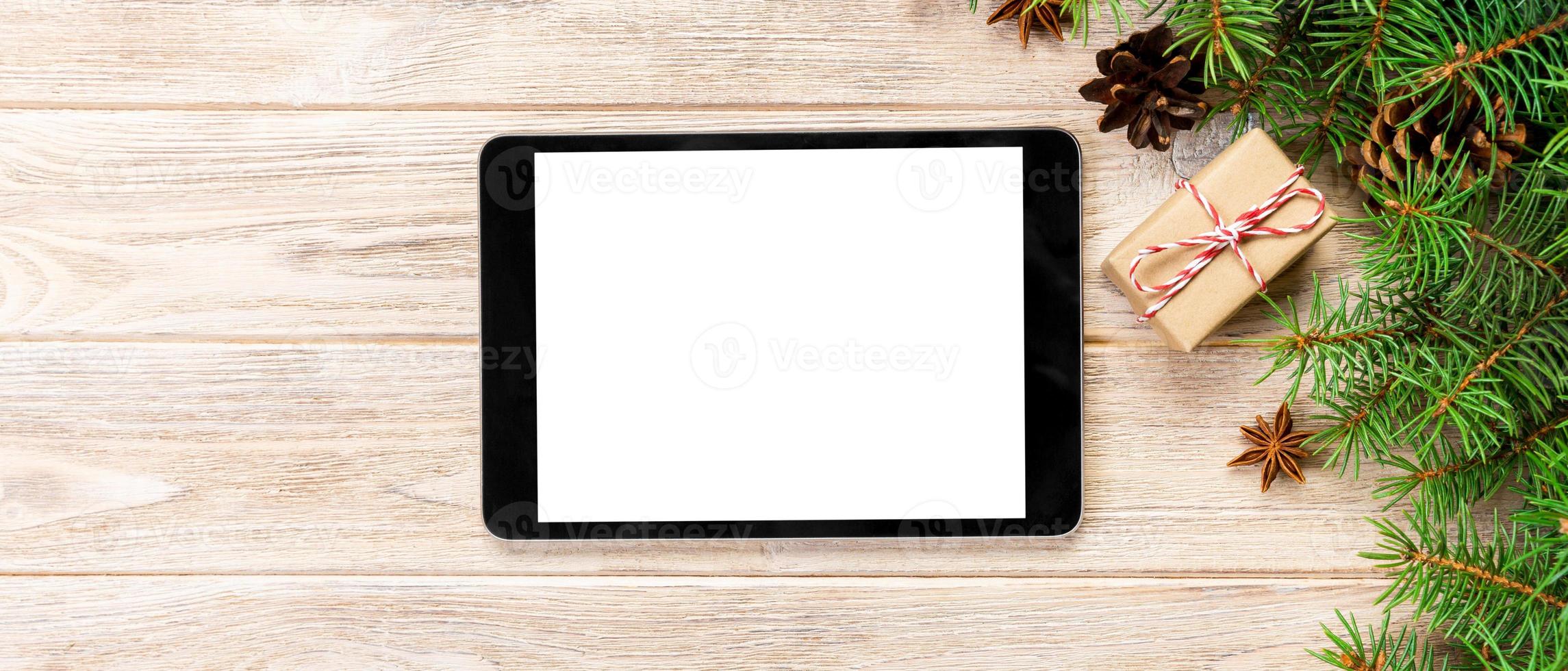 Digital tablet mock up with rustic Christmas wooden background decorations for app presentation. top view with banner copy space photo