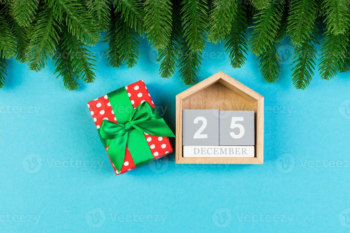 Top view of wooden calendar, gift box and fir tree on colorful background. The twenty fifth of December. Christmas time with copy space photo