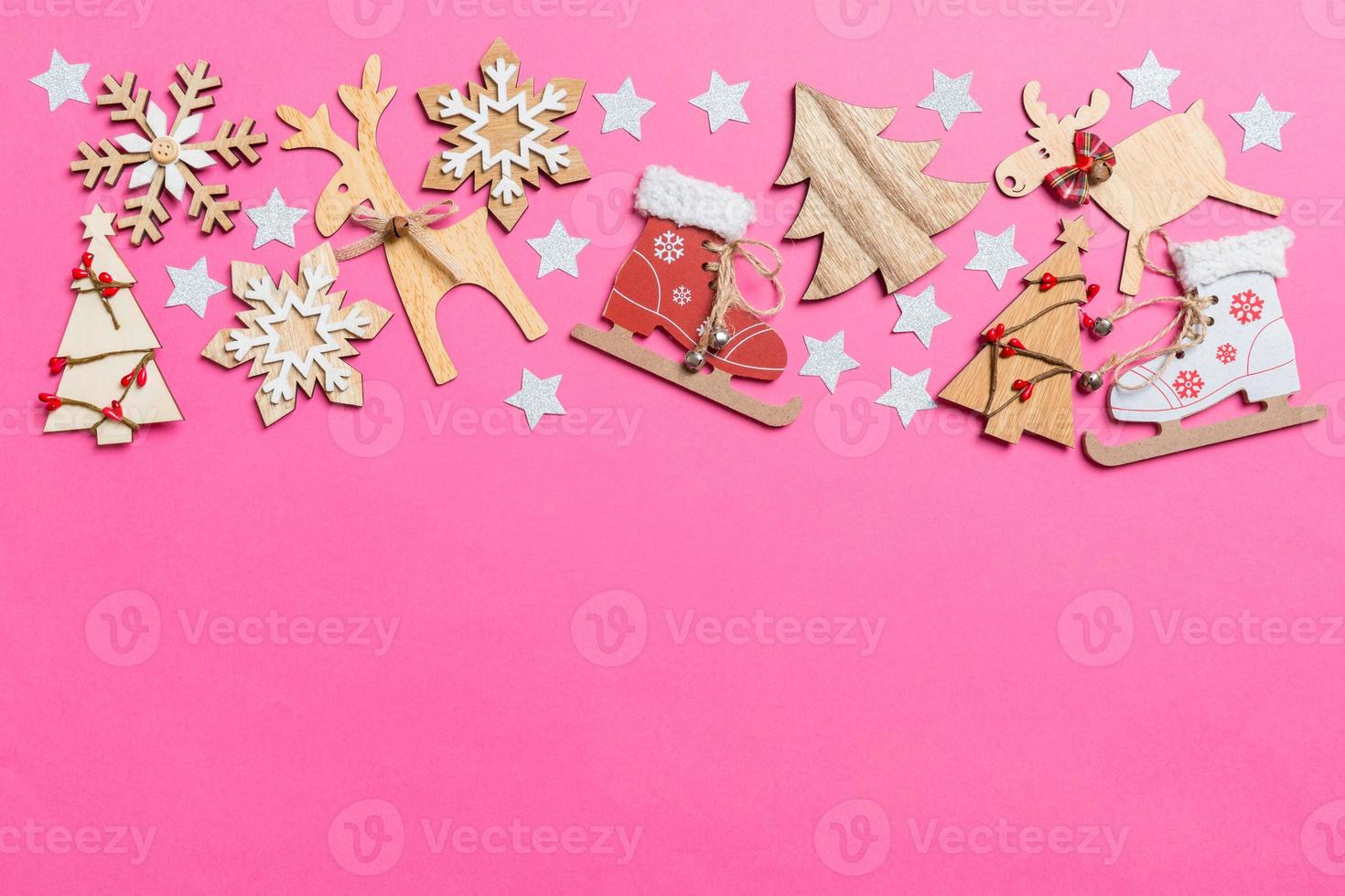 Top view of pink background decorated with festive toys and Christmas symbols reindeers and New Year trees. Holiday concept with copy space photo