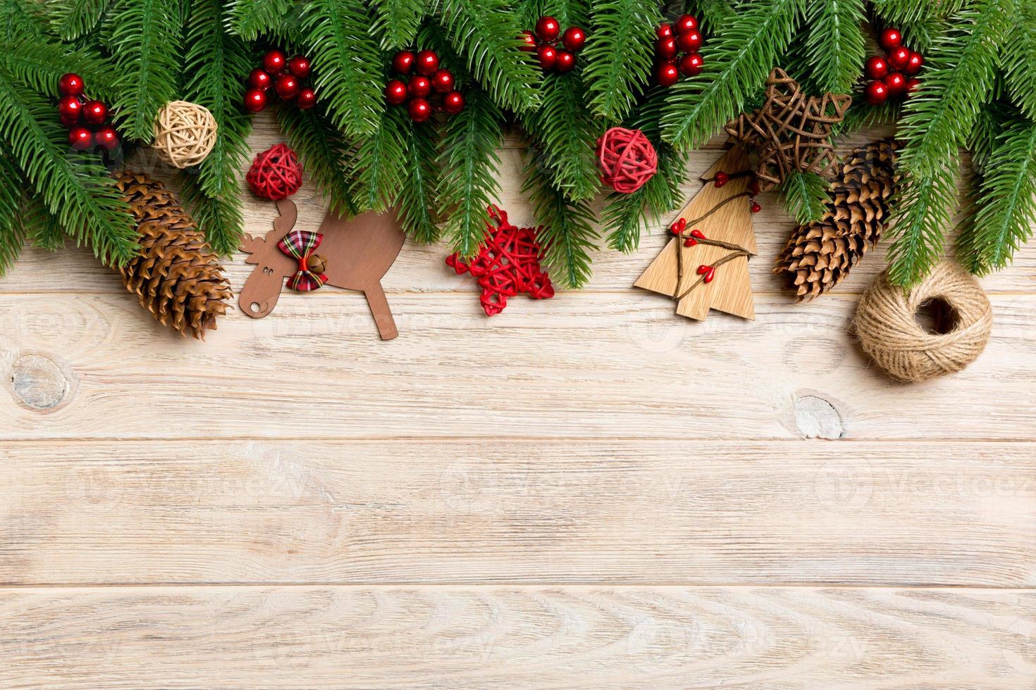 Top view of Christmas toys, decorations and fir tree branches on wooden background. New Year holiday concept with copy space photo