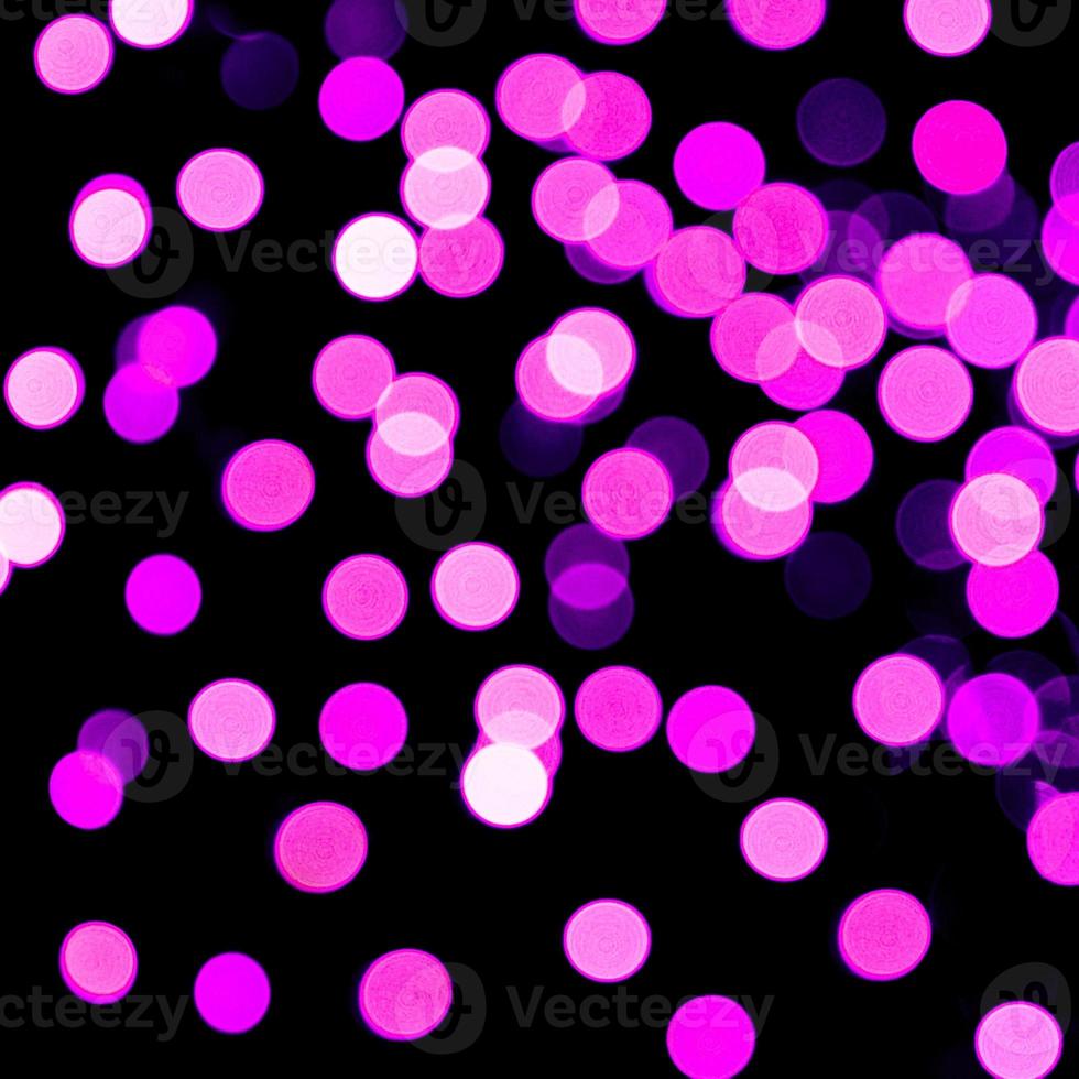 Unfocused abstract purple bokeh on black background. defocused and blurred many round light photo