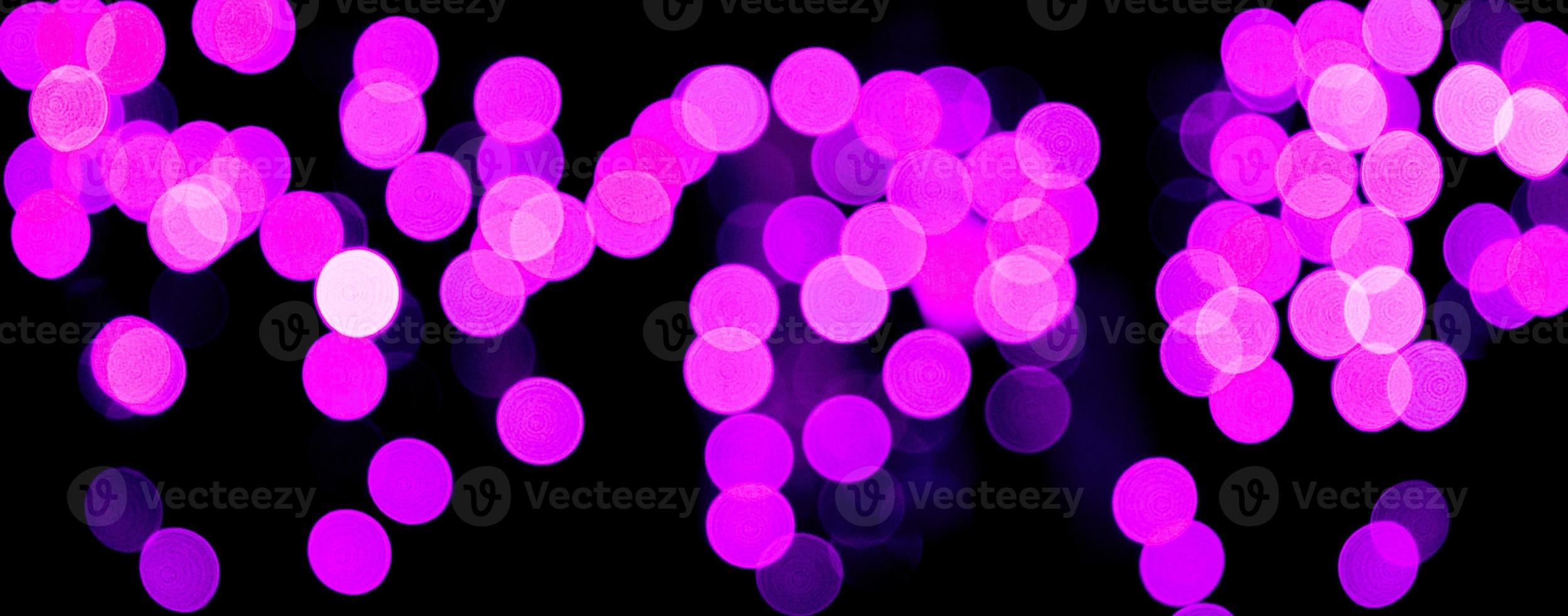Unfocused abstract purple bokeh on black background. defocused and blurred many round light photo