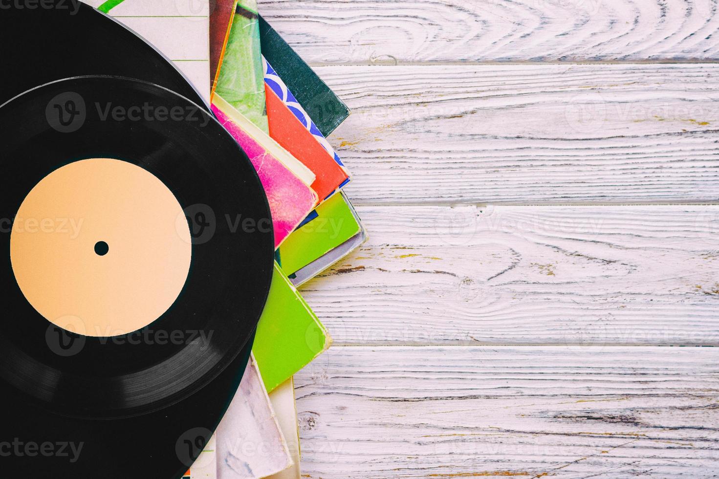 Retro styled image of a collection of old vinyl record lp's with sleeves on a wooden background with Copy space top view toned photo