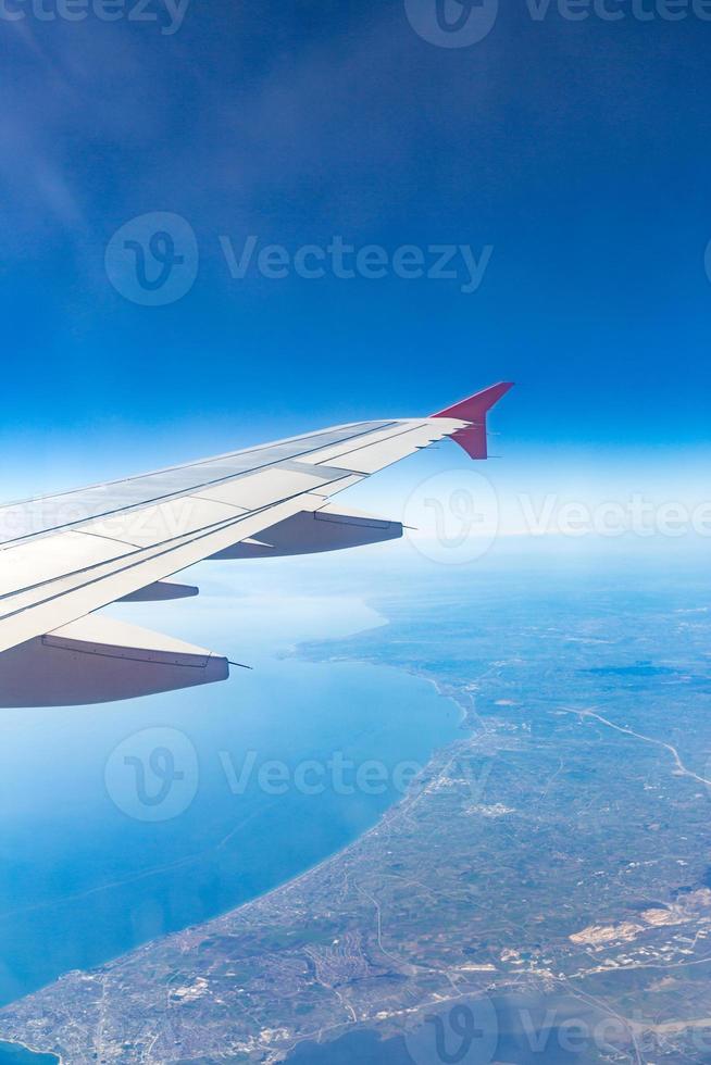 Aircraft wing on the clouds, flies on the city background photo