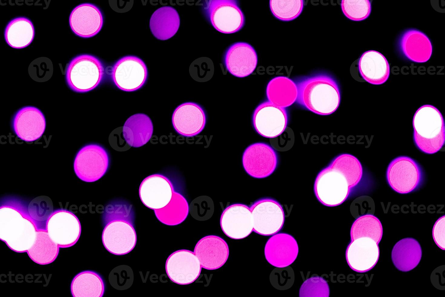 Unfocused abstract purple bokeh on black background. defocused and blurred many round light photo
