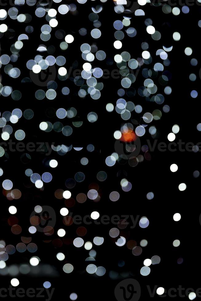 Bokeh white lights on black background, defocused and blurred many round light on background photo