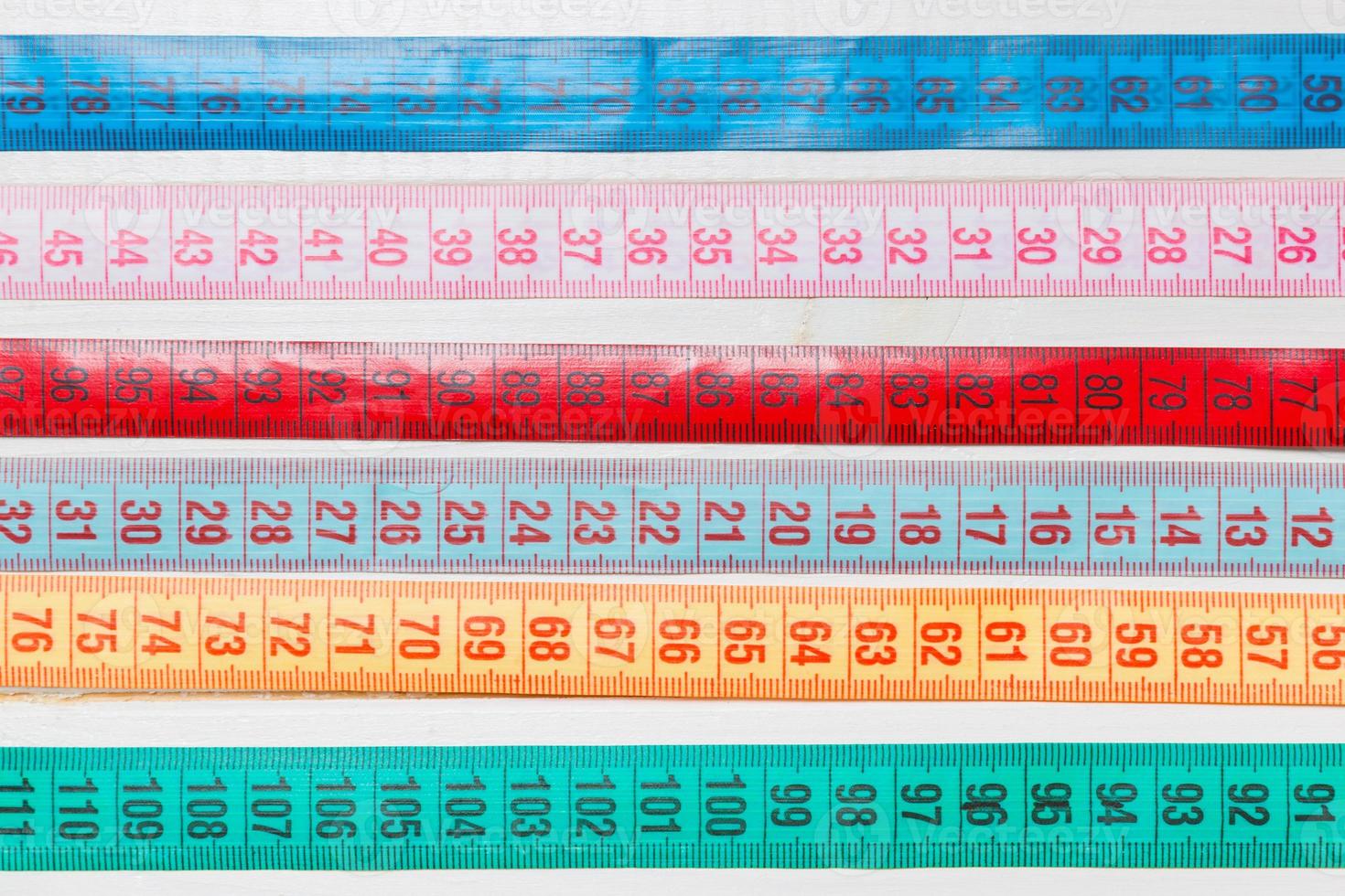 Close up of a group of colorful measure tapes lying in rows as a background. Diet concept on wooden background photo