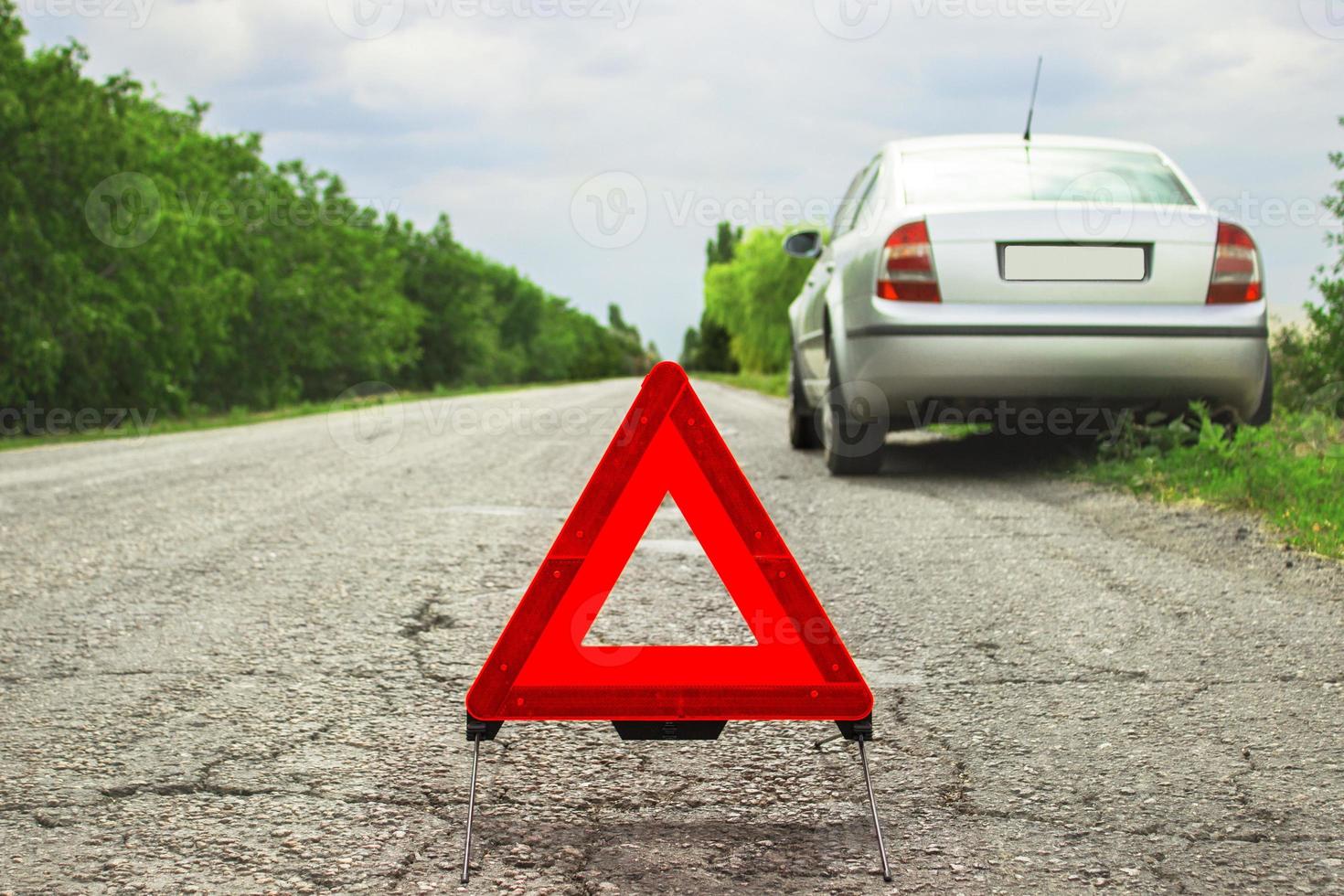 Red triangle of a car on the road. Car warning triangle on the road against the city in the evening. Breakdown of the car in bad weather. photo