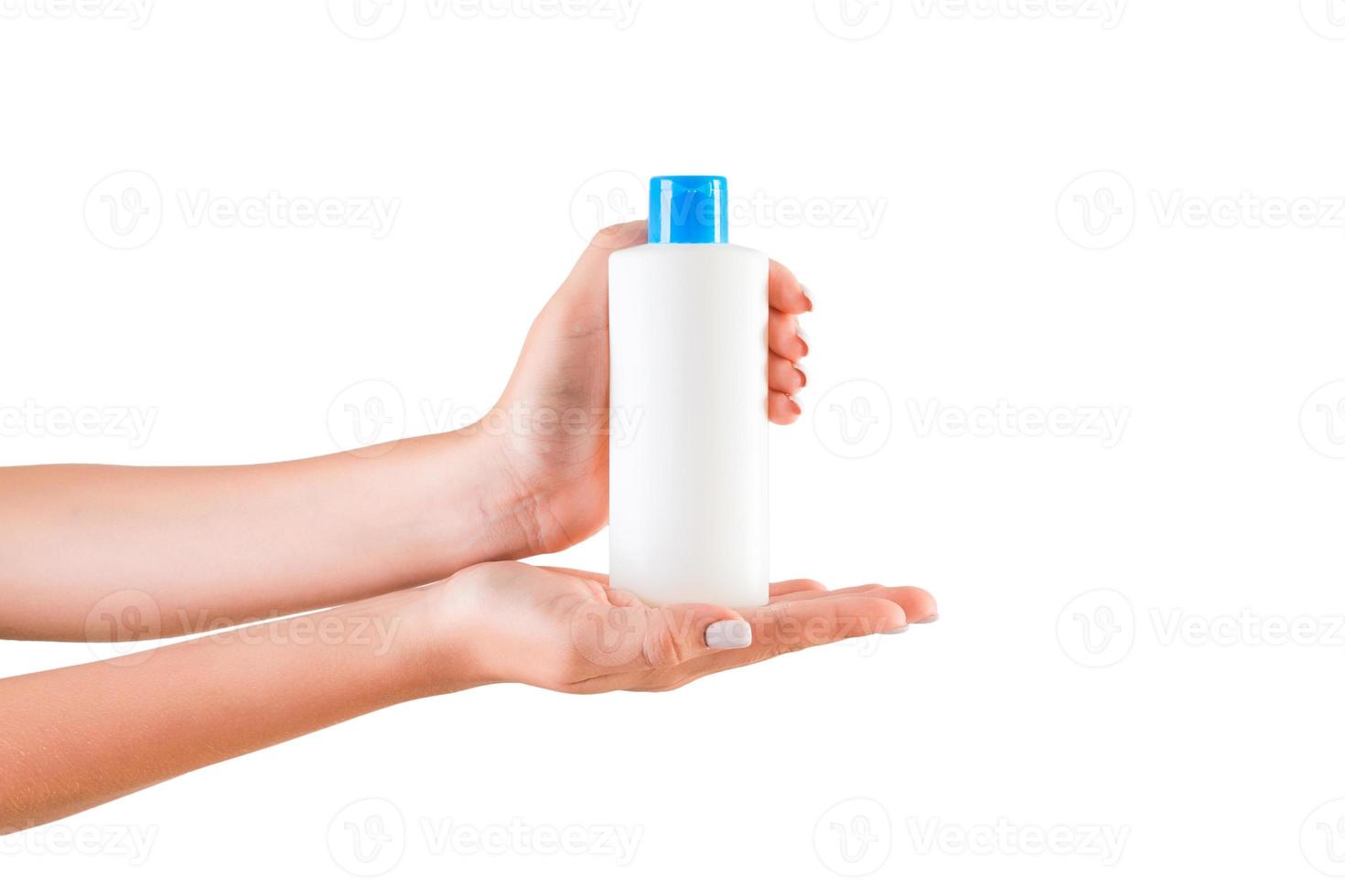 mano femenina sosteniendo una botella de crema de loción aislada. Chica dar productos cosméticos sobre fondo blanco. foto