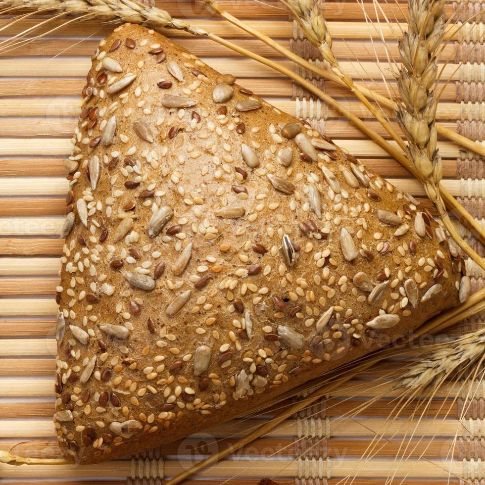 varios pequeños panes triangulares multigrano rociados con semillas enteras de girasol, semillas de lino y sésamo y espigas de trigo y cebada foto