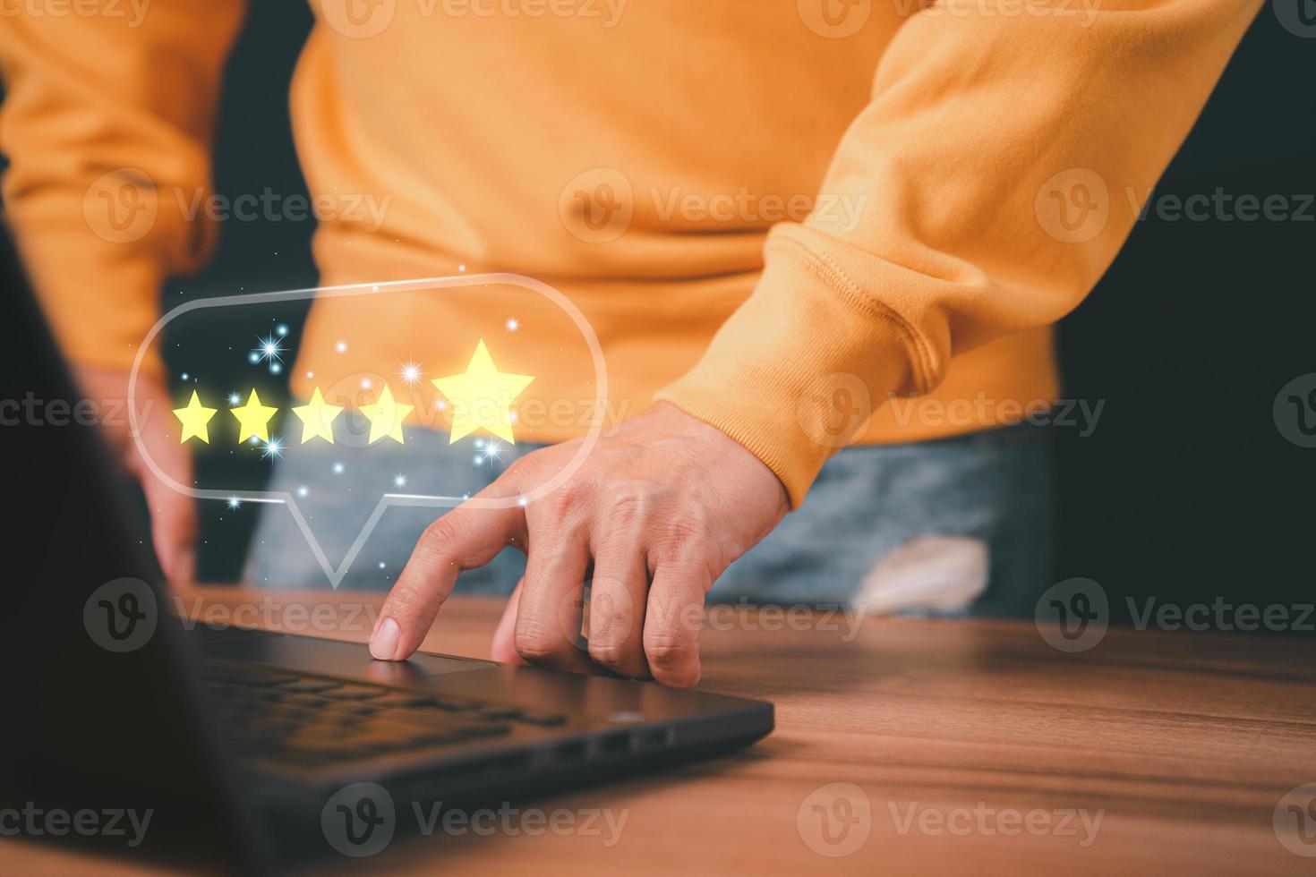 Man hand using computer laptop with popup five star icon for feedback review satisfaction service, testimonial. Customer service experience and business satisfaction survey. photo