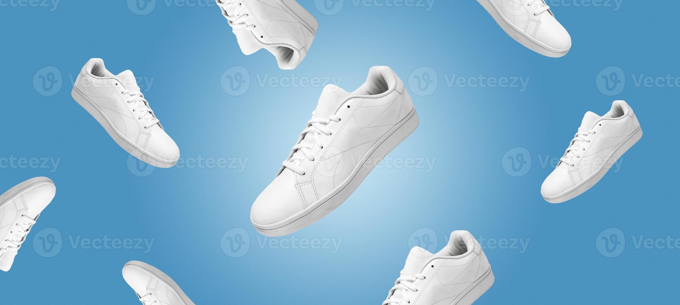 Banner with pattern of white sneakers isolated on blue background. Sportive pair of shoes for mockup. Fashionable stylish sports casual shoes. Modern and minimalist wallpaper of fashion lifestyle. photo