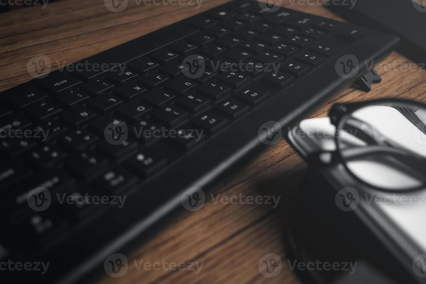 Top view of wood vintage desk focused on laptop with notepad, smartphone and glasses. Workplace. Work from home. Office desk. photo