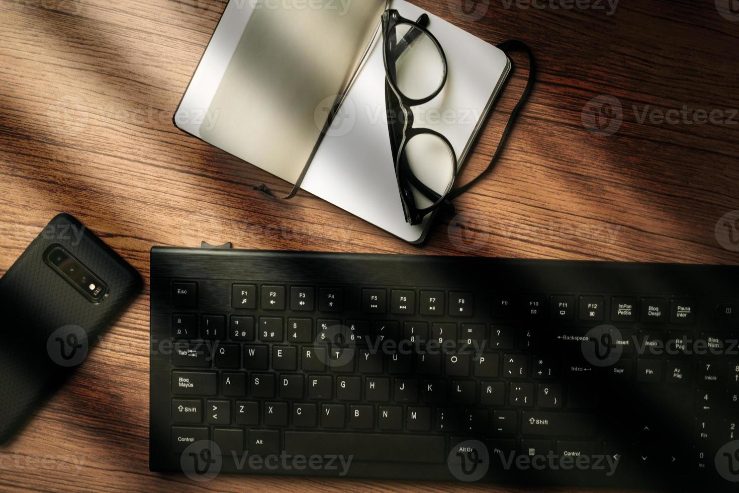 Top view of wood vintage desk focused on laptop with notepad, smartphone and glasses. Workplace. Work from home. Office desk. photo