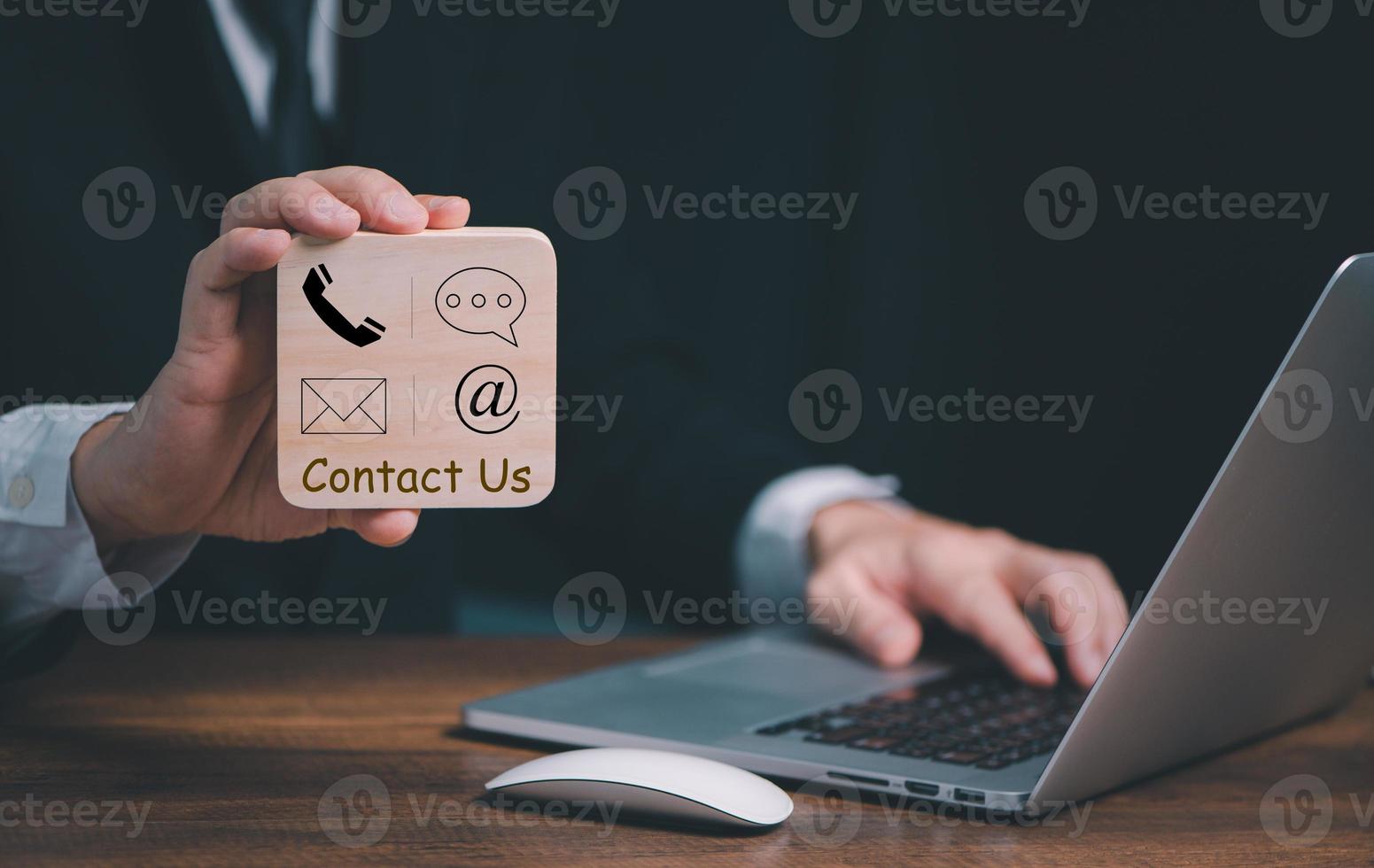 CONTACT US, Hand of Businessman holding wooden block with  mail,phone,email, chat icons. Business customer support and service concept, copy space. photo