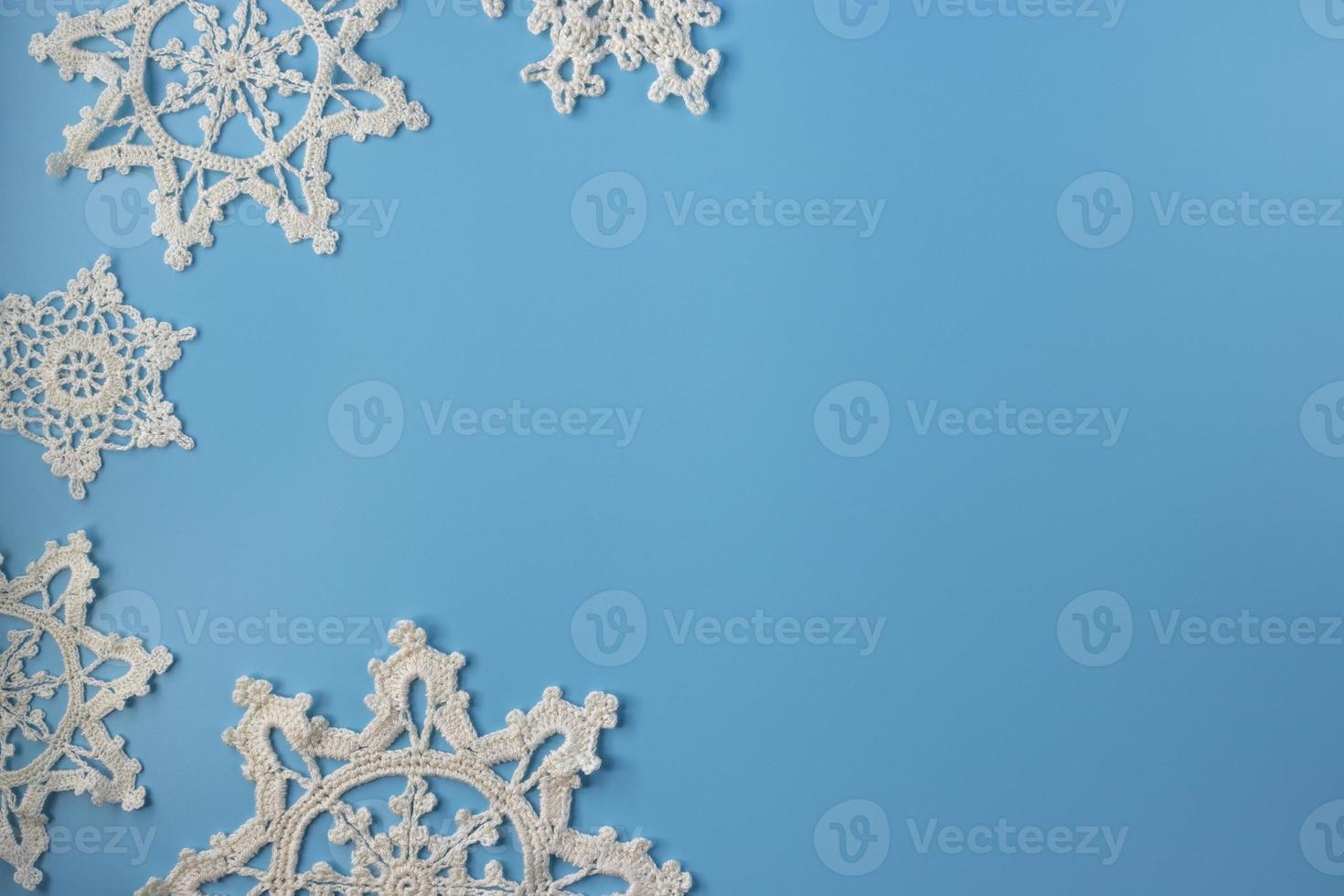 Top view of handmade white crochet  snowflakes on blue background. Merry Christmas and happy new year concept. photo
