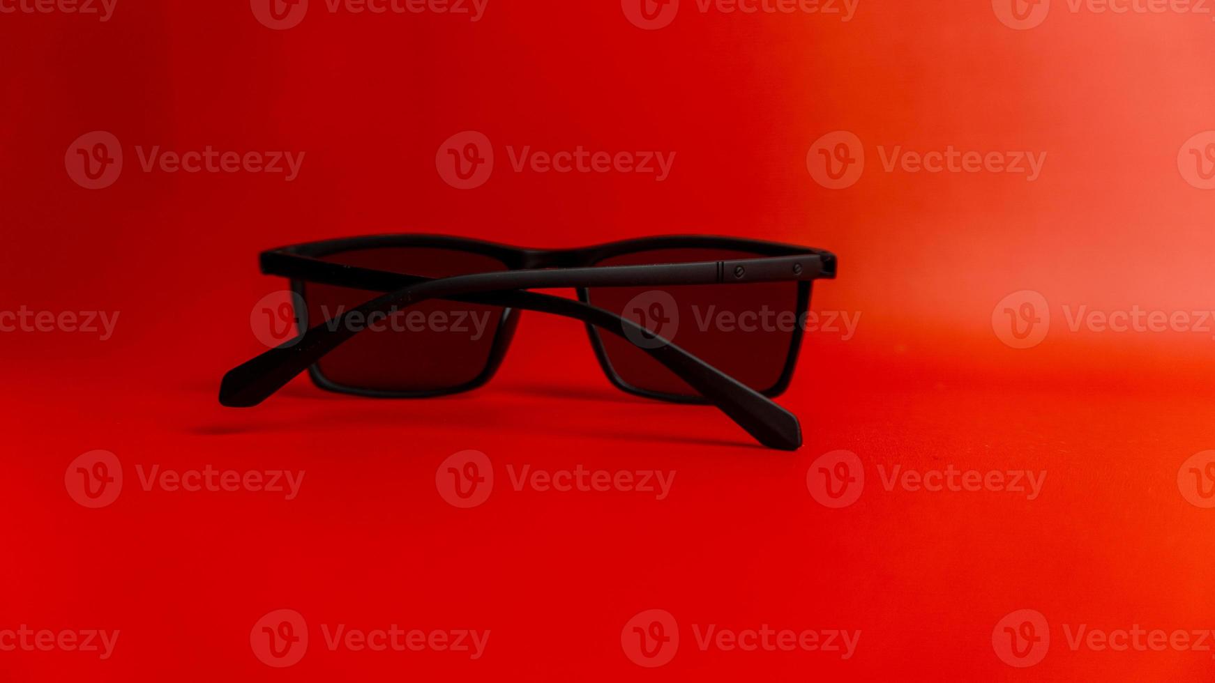 Black sunglasses on red background photo