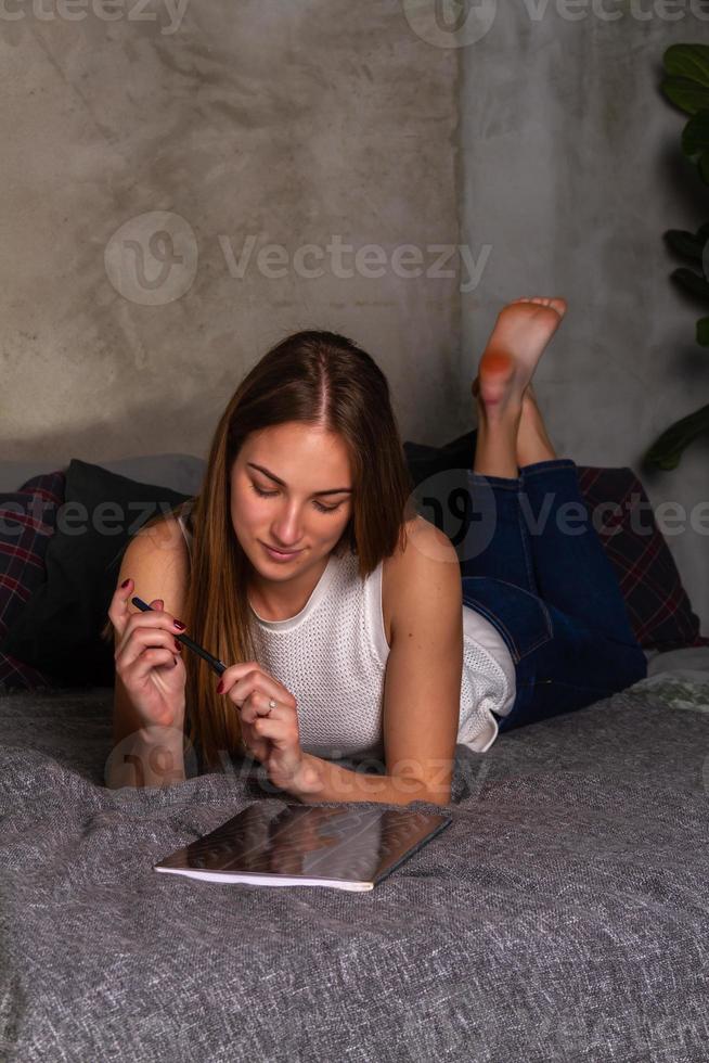 mujer soñando acostada boca abajo en la cama con un cuaderno foto