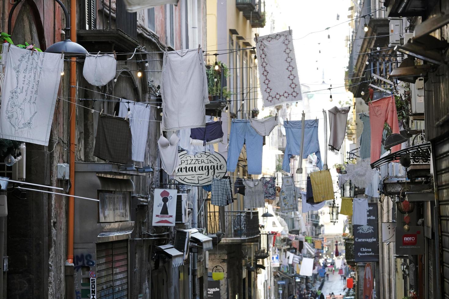 calle en nápoles, italia, con ropa colgada de cuerdas que la atraviesan foto