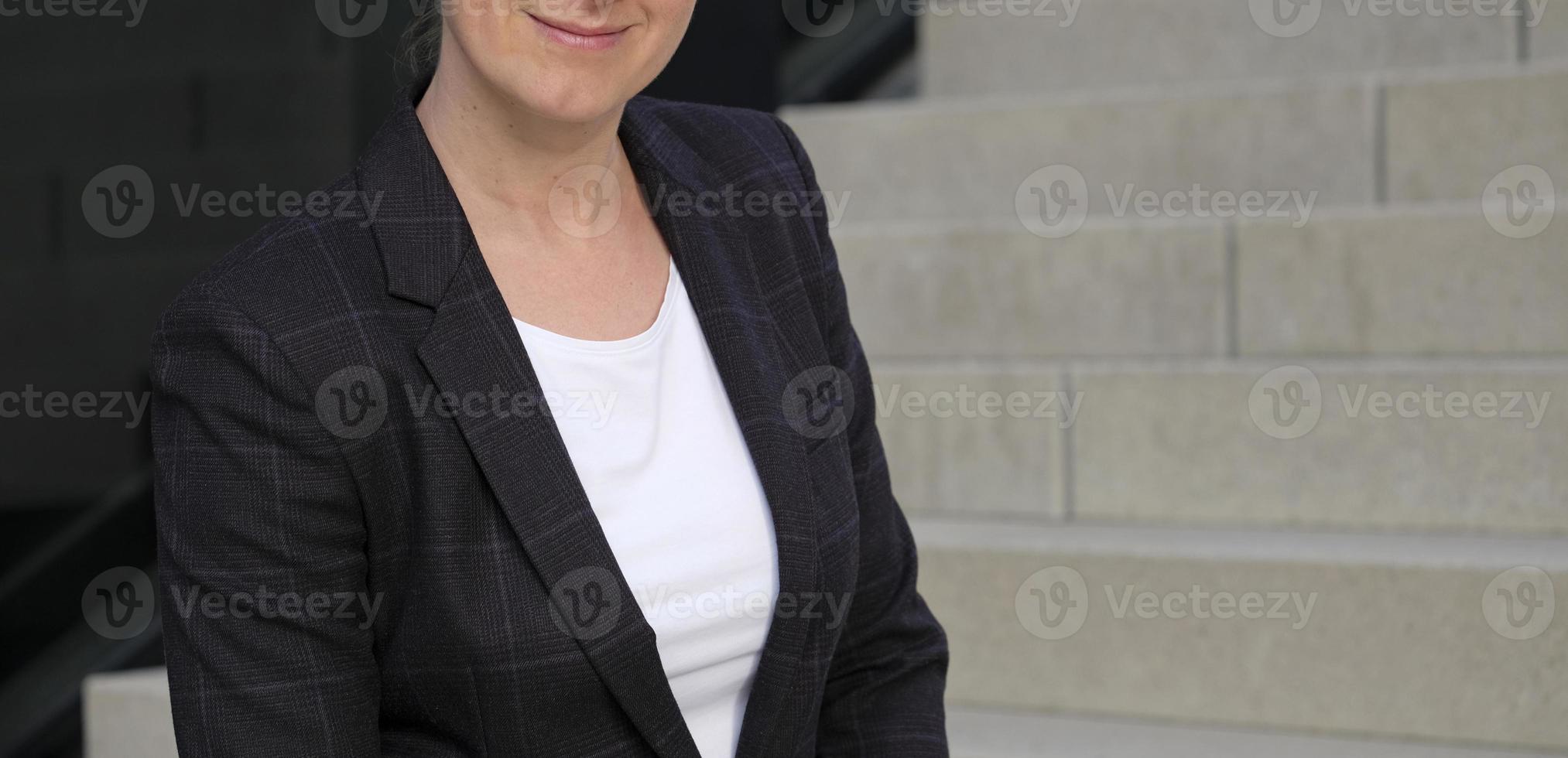 Female professional in a white shirt and black suit jacket with an urban background photo