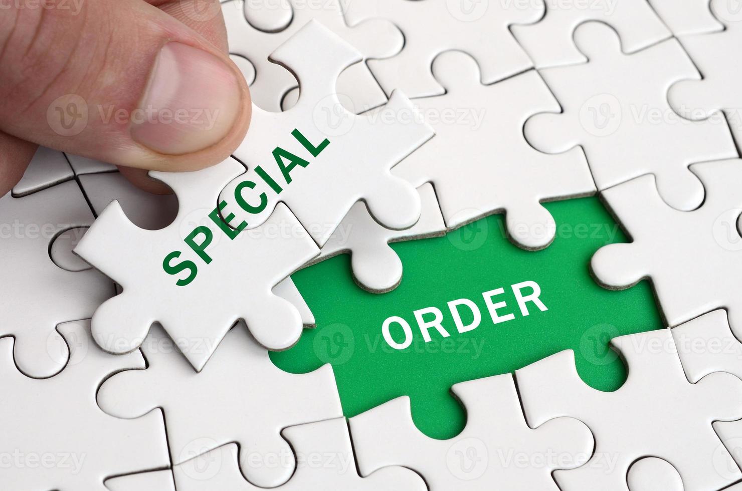 The human hand fills the last missing elements of the surface from the jigsaw puzzle. Image with words special and order photo