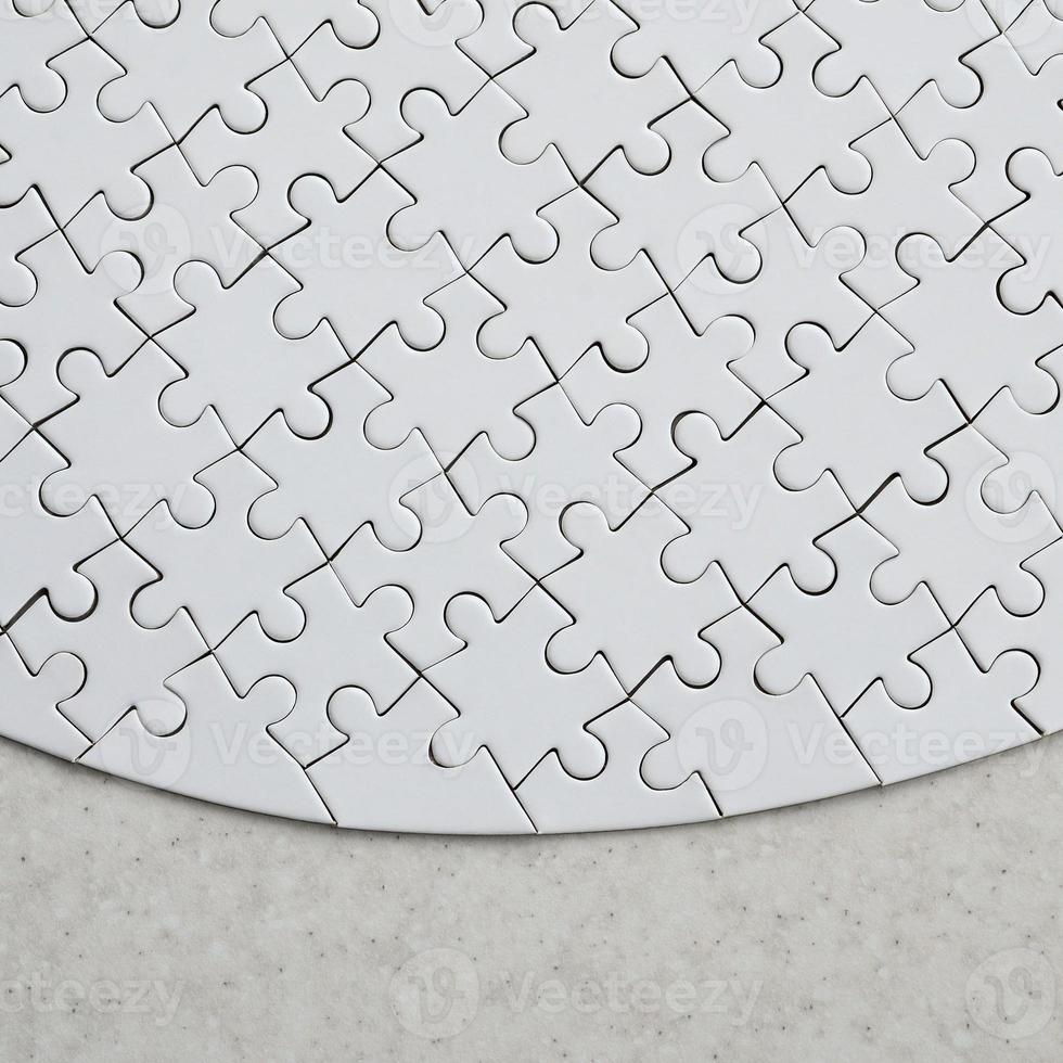A white jigsaw puzzle in the complete form lies on a treated stone surface. Textured image with copy space photo