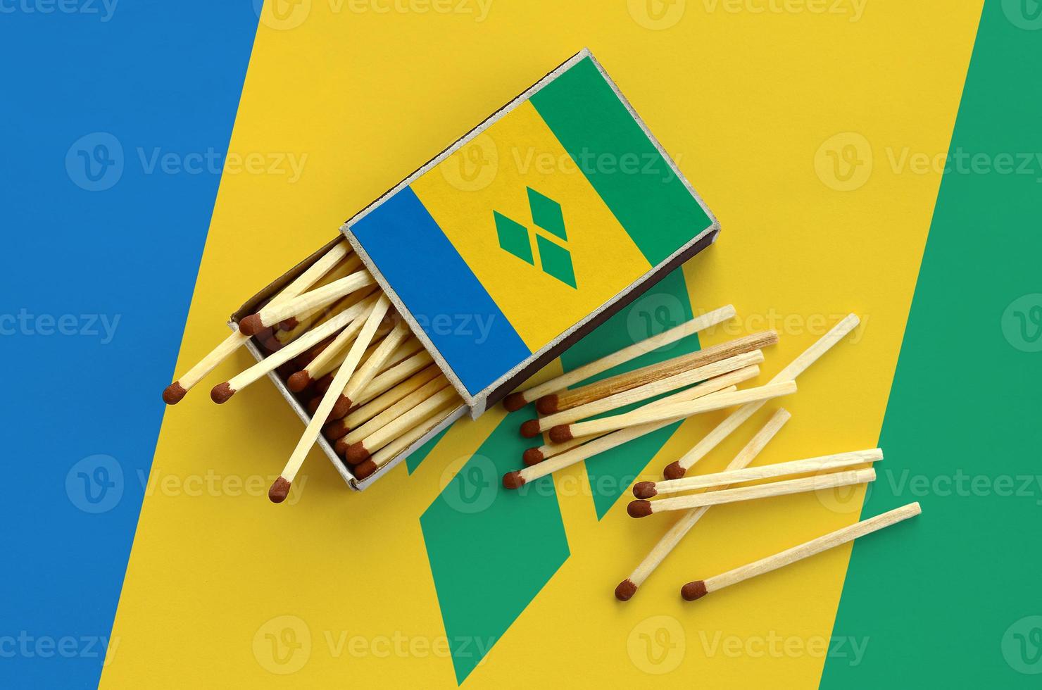 Saint Vincent and the Grenadines flag is shown on an open matchbox, from which several matches fall and lies on a large flag photo