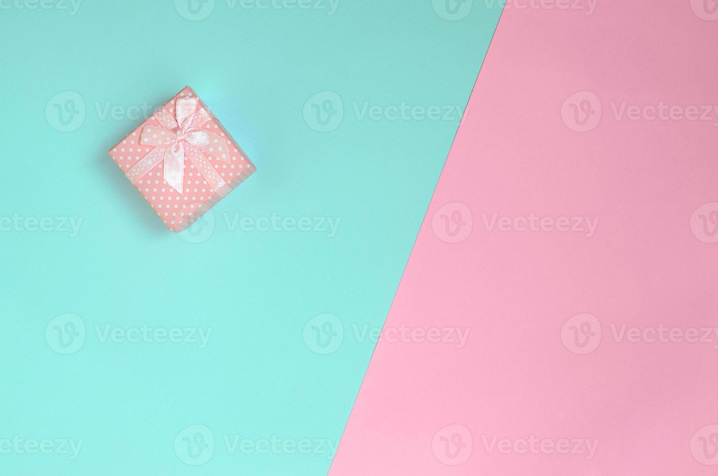 Small pink gift box lie on texture background of fashion pastel blue and pink colors paper in minimal concept photo